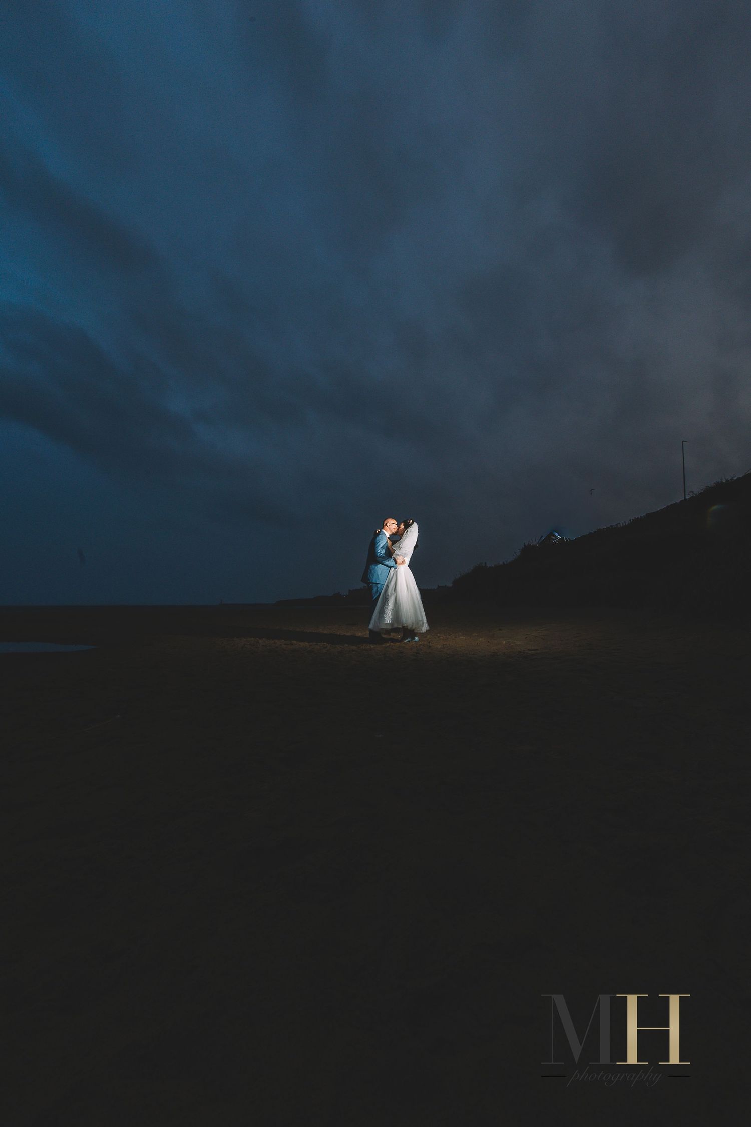 Dark moody landscape photo with glowing letters M and H against a dramatic night sky.