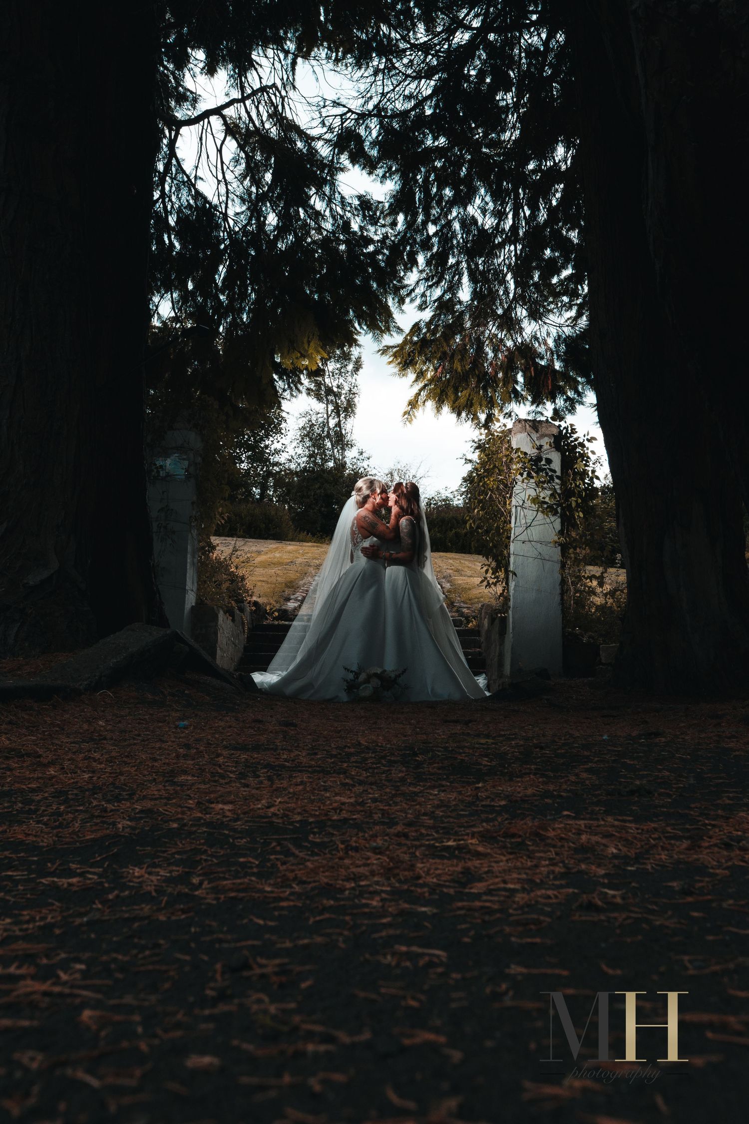 Atmospheric sunset wedding photo with couple silhouetted against trees.