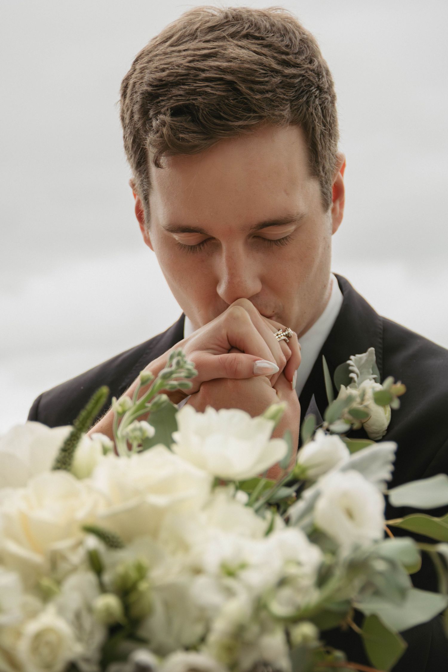 Romantic groom wedding photography pennsylvania lehigh valley groom kissing bride's hand showing off ring with bridal bouquet in foreground