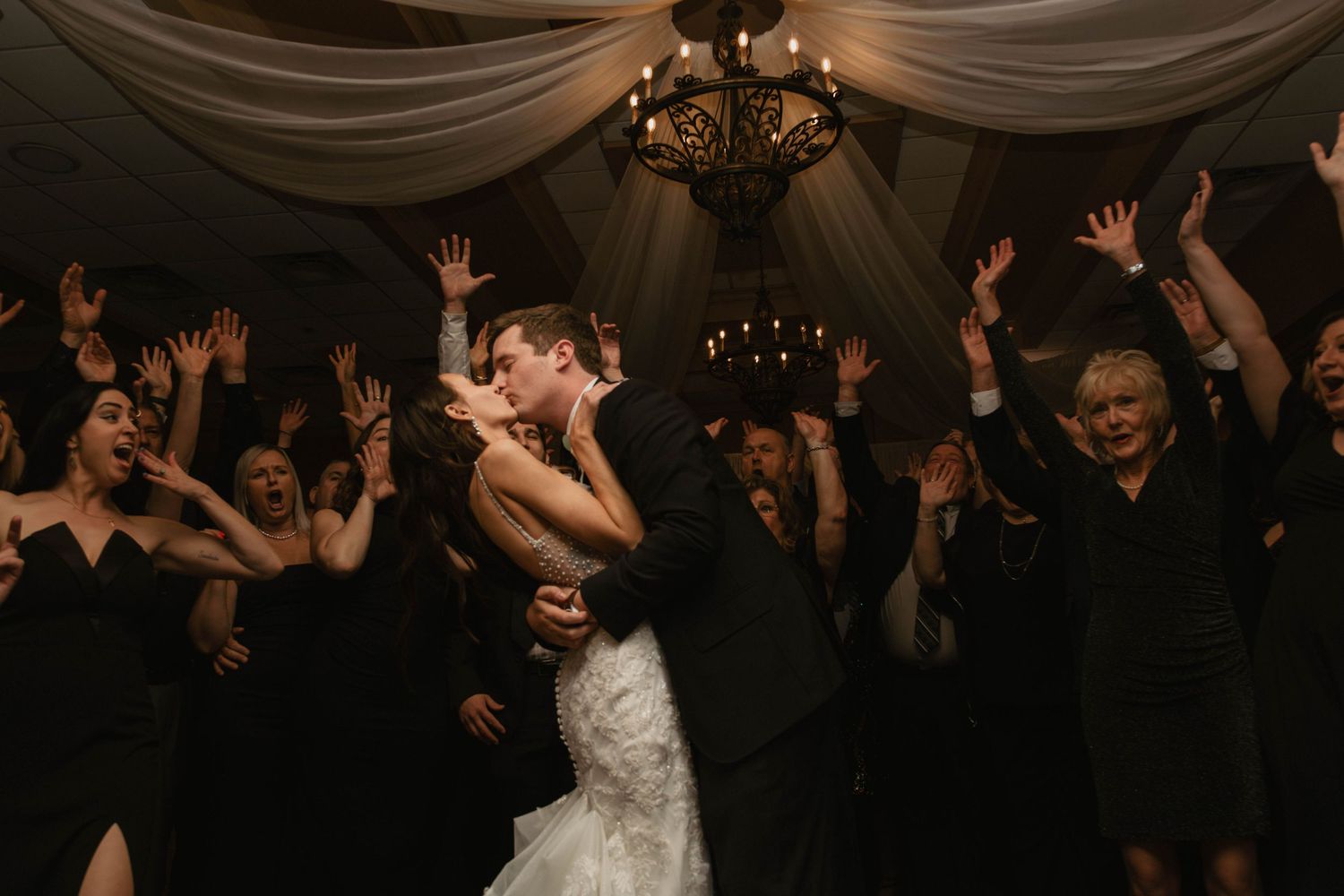 Candid in the moment joyous wedding reception photos bride and groom kiss with wedding guests in background lehigh valley Pennsylvania pics