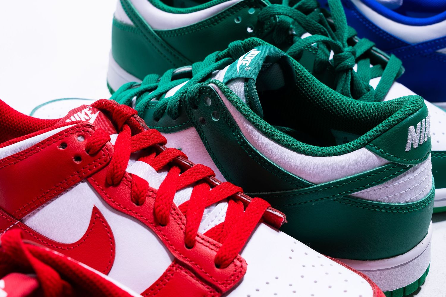 Close-up of red and green Nike Dunk Low sneakers showing distinctive colorways and details.