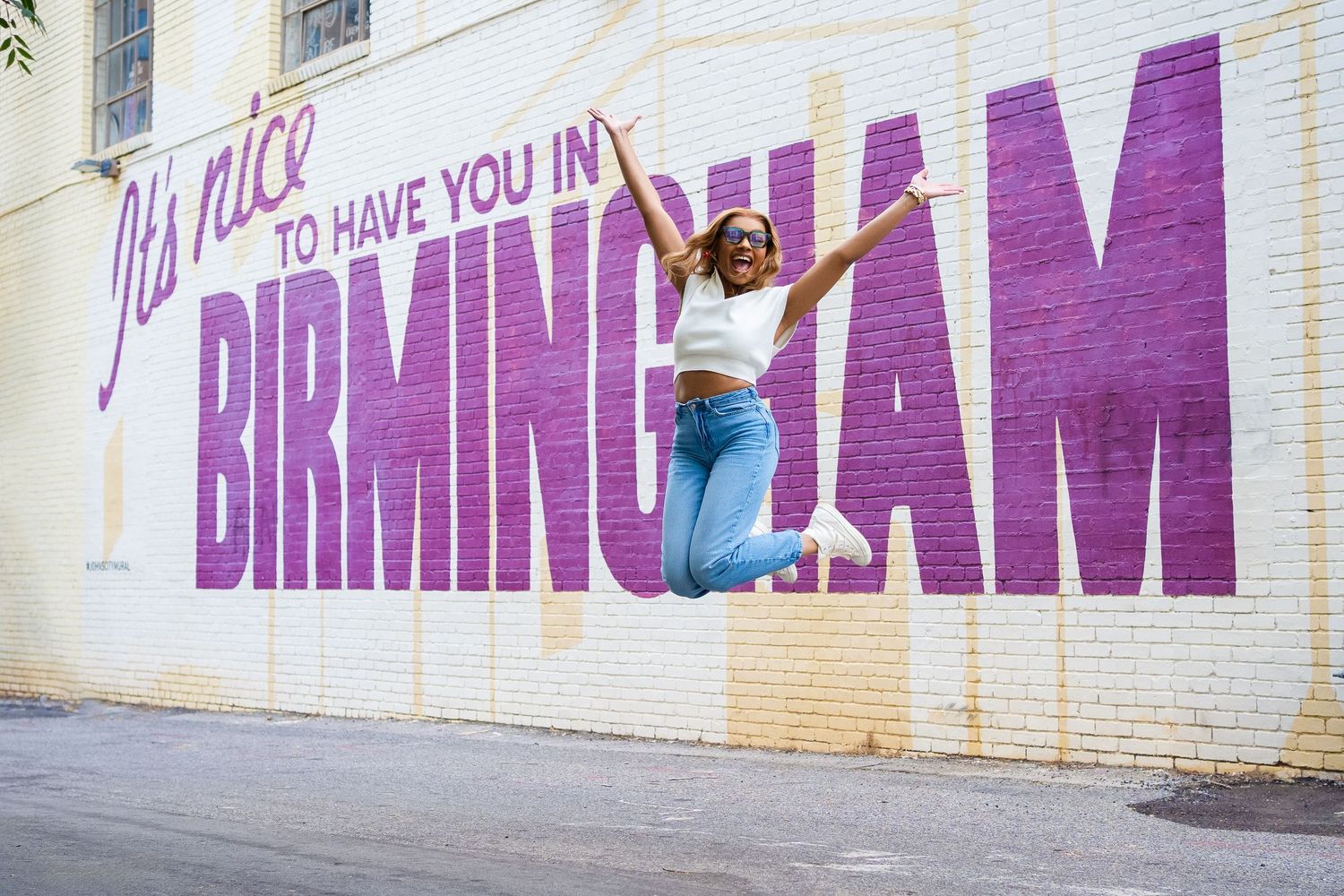 Purple text graffiti spelling 'BIRMINGHAM' on a white wall.