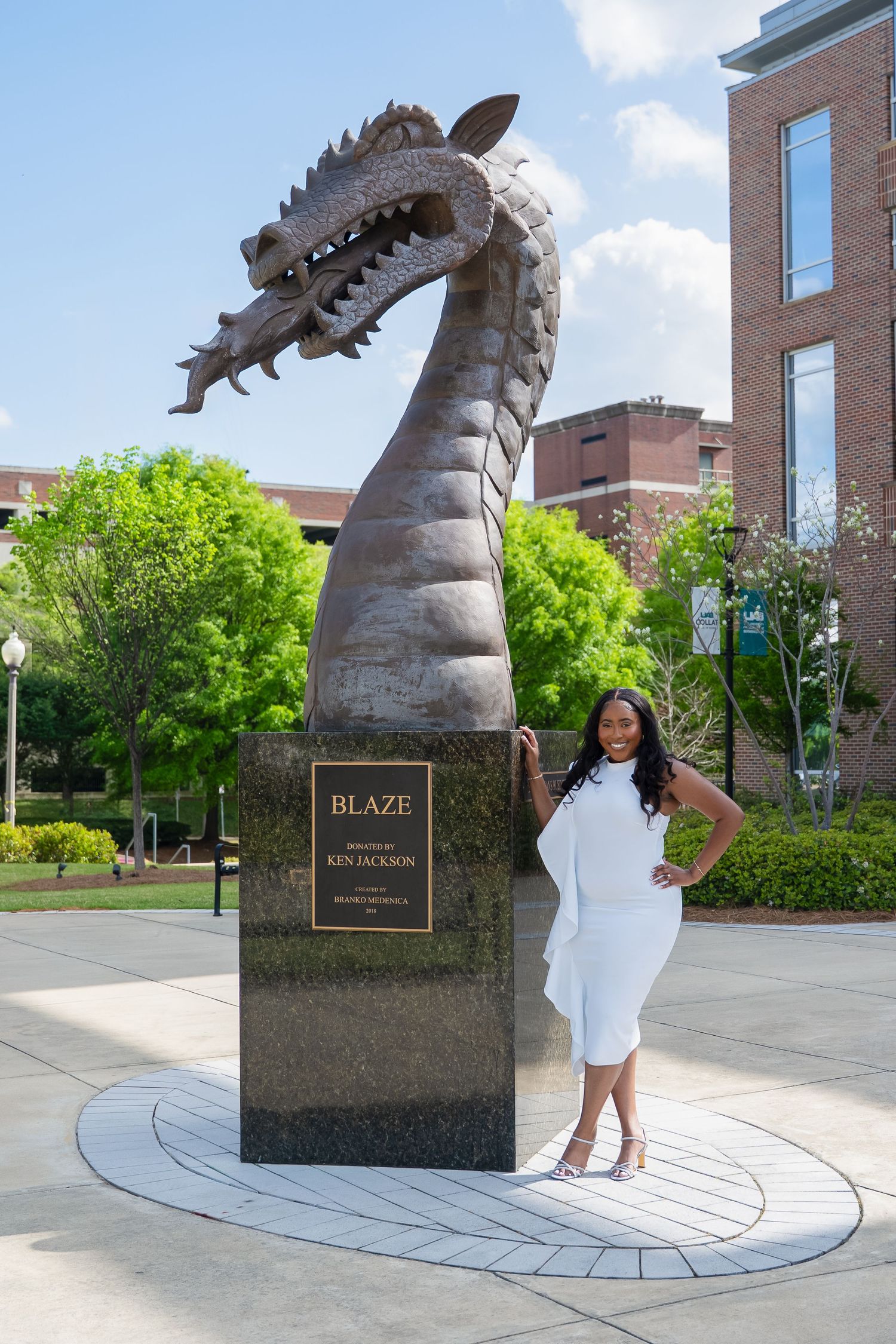Large dragon sculpture installation outside brick campus building.