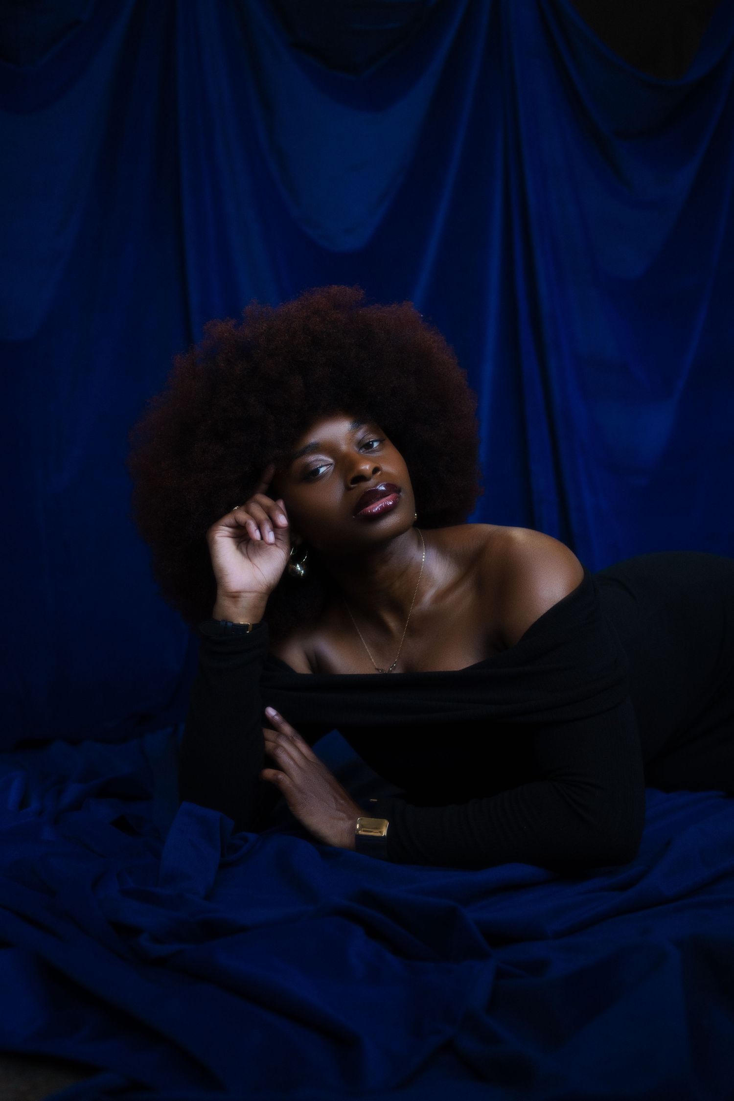 A series of artistic portraits against a dark blue backdrop showing dramatic poses and expressions in low light.