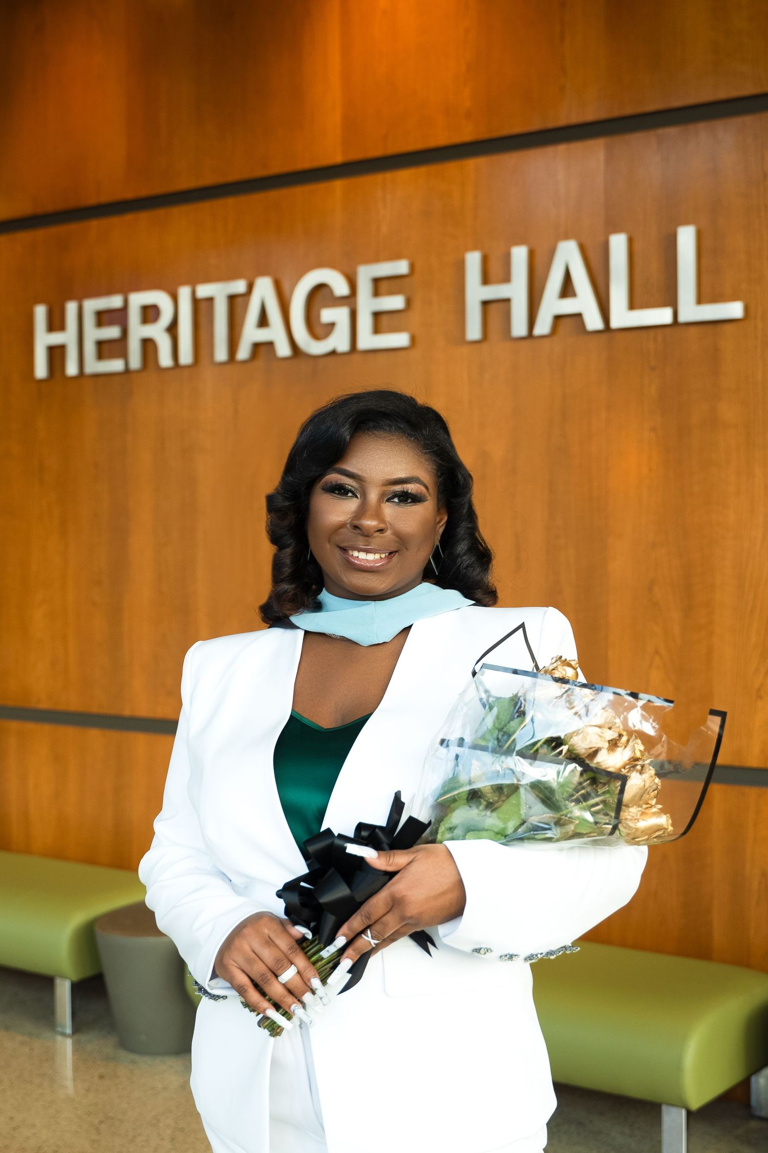 Professional in white blazer holds flowers at Heritage Hall.
