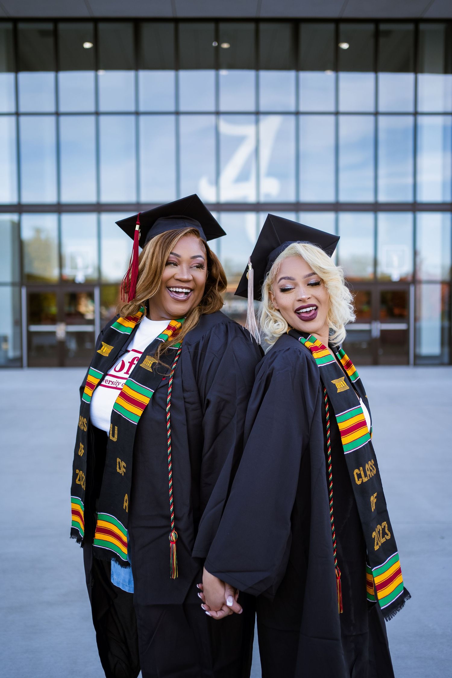 Graduation celebration photos showing graduates wearing black gowns and colorful kente stoles outside a modern building.
