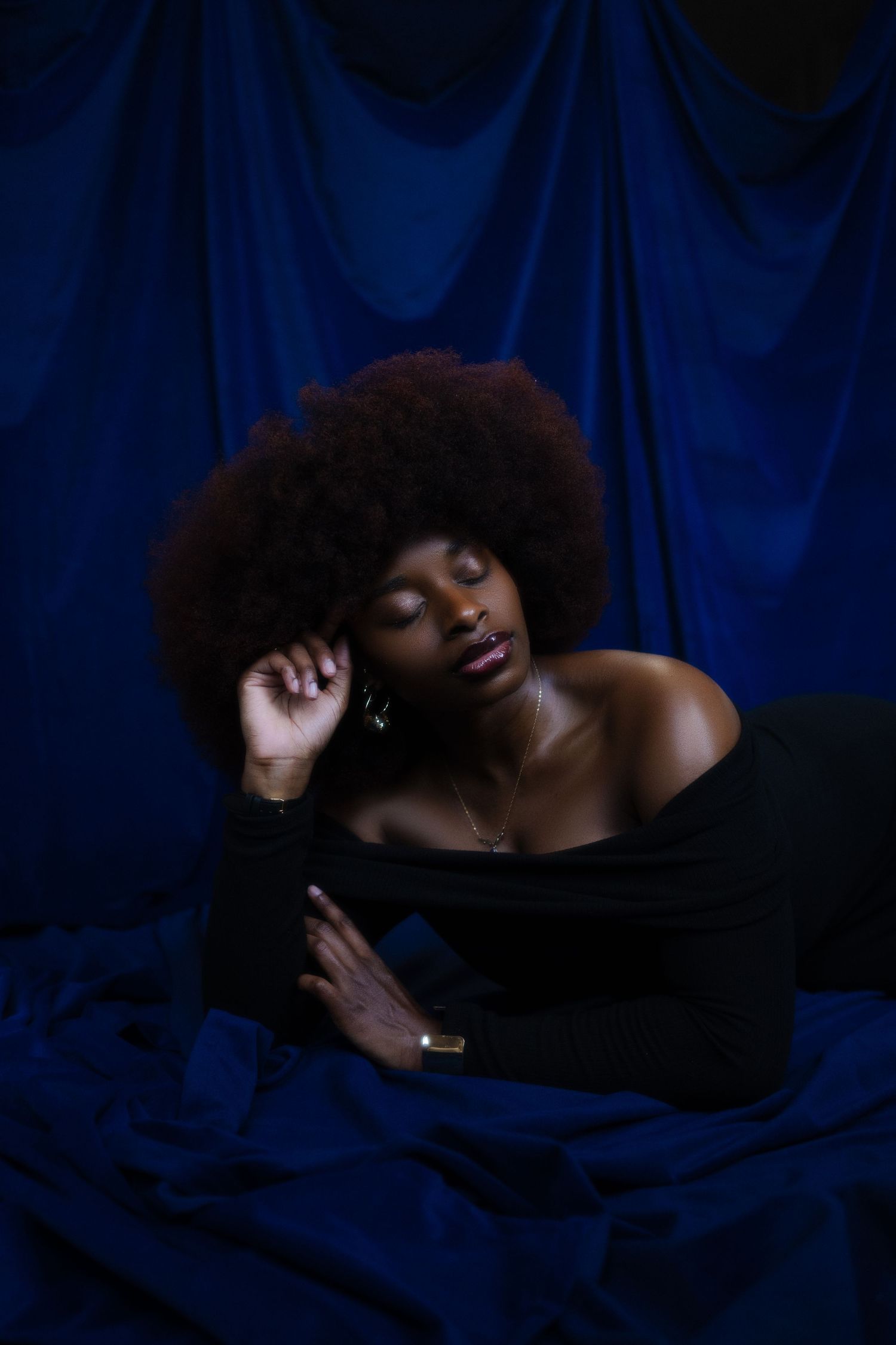 Artistic portrait series against dark blue fabric backdrop showing dramatic poses in low-key lighting.