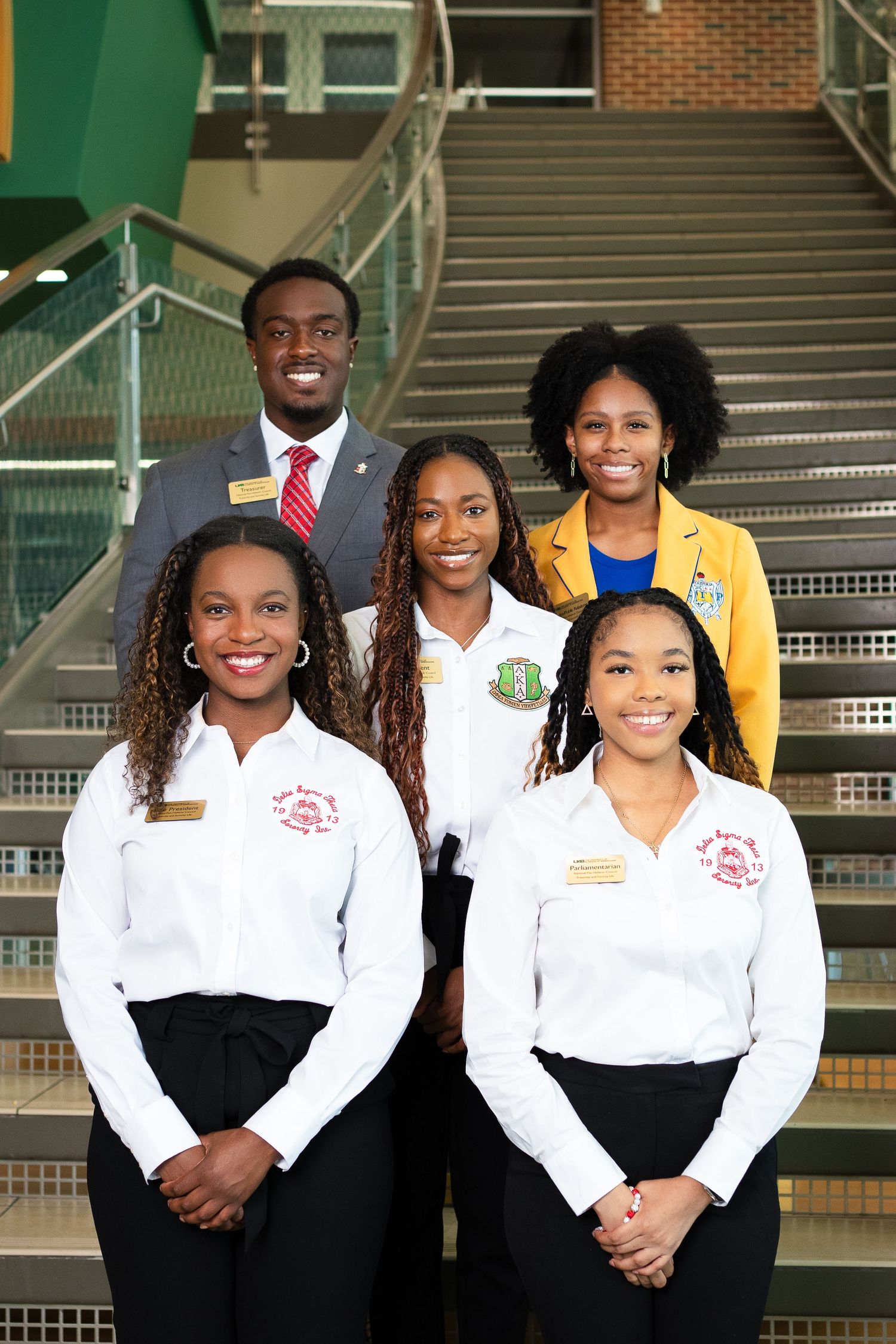 Formal group photo of students in professional attire on campus steps.