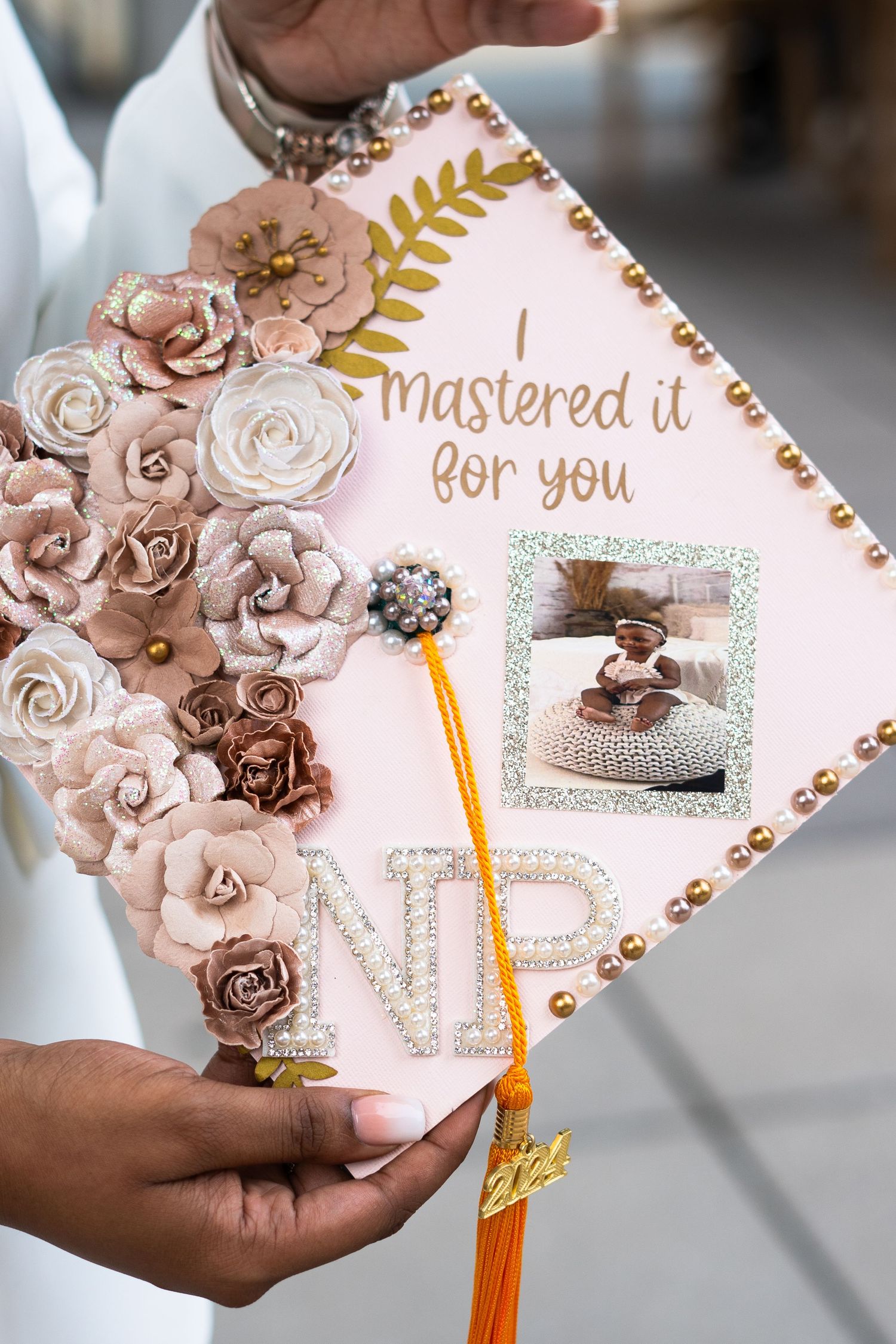 Decorated graduation cap with pink paper flowers and glitter details.