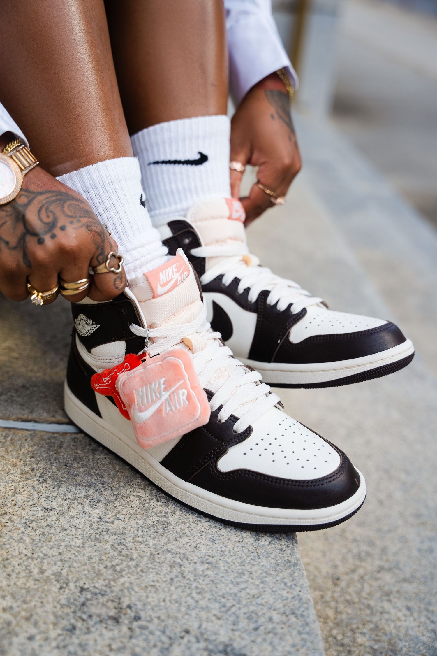 Close-up shots of Nike sneakers in black, white and coral pink colorway shown from different angles on feet.