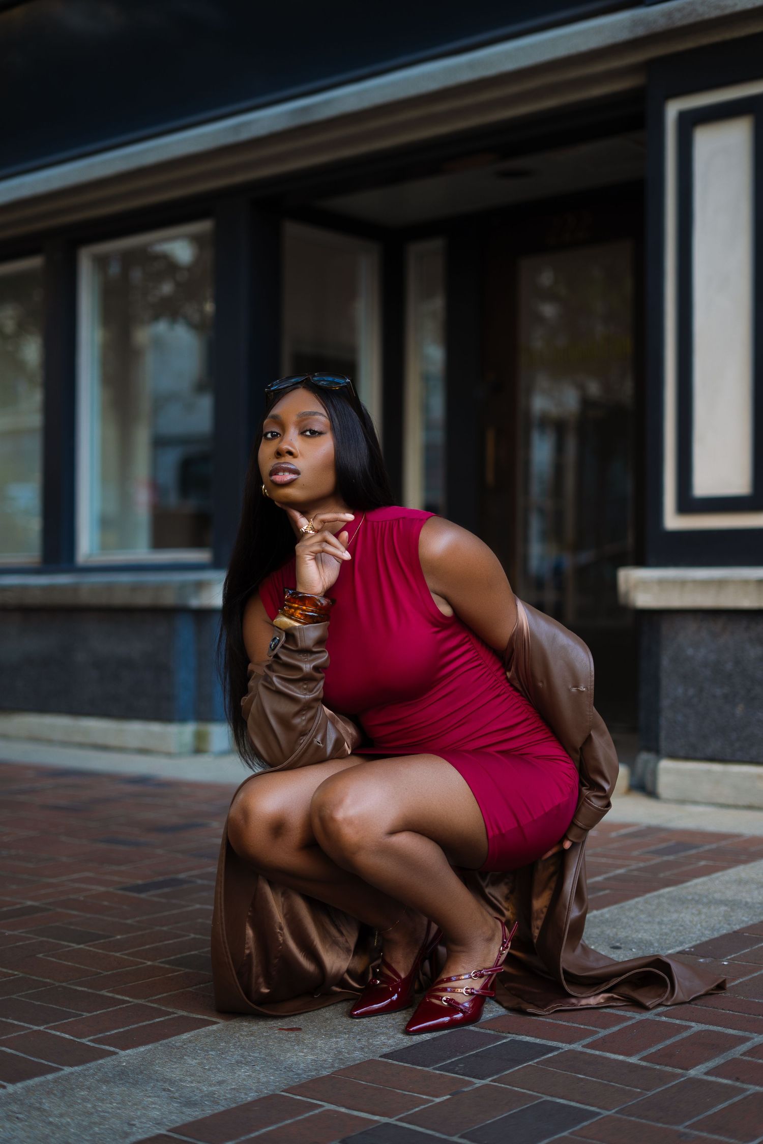 A person in a red dress crouches low on tiled ground in an artistic photo series.