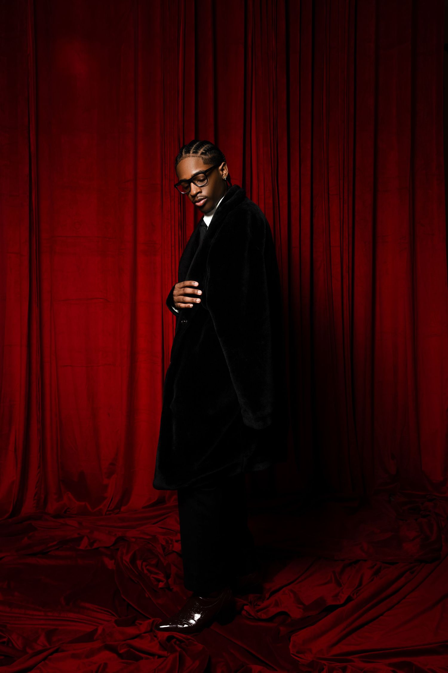 A person in a black outfit poses against a dramatic red curtain backdrop in a series of artistic portrait shots.