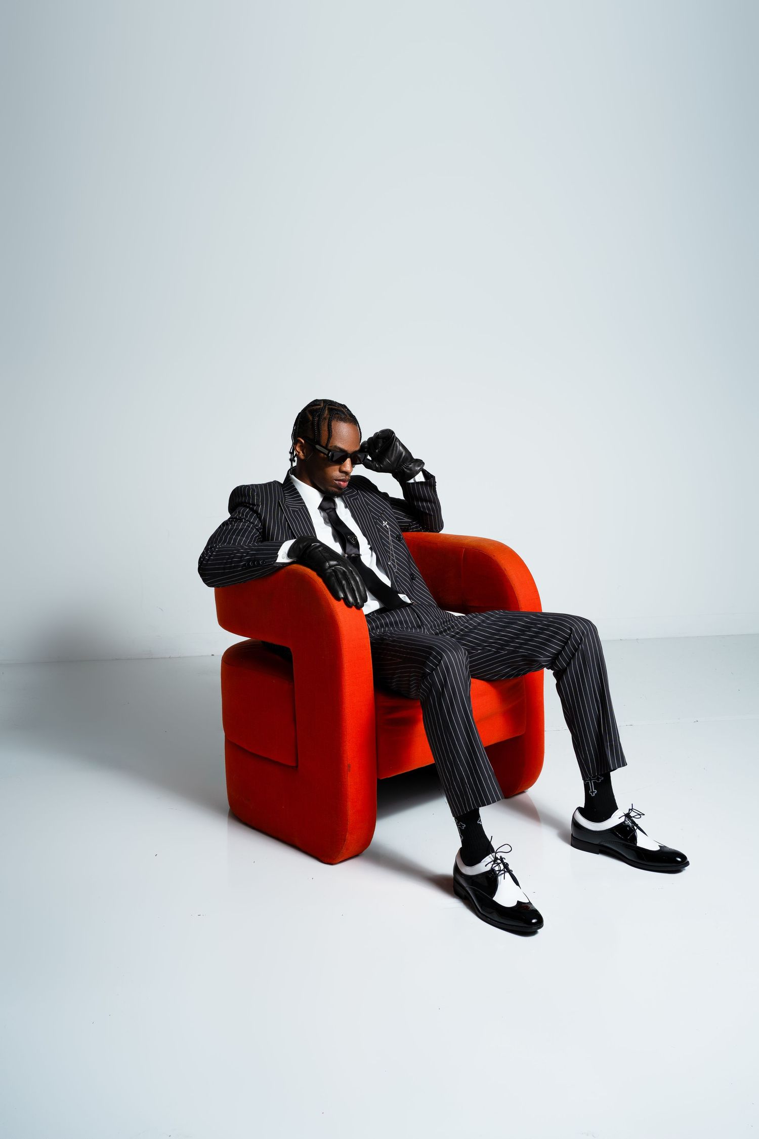 A series of photos showing a figure in black clothing reclining on a bright red armchair against a white background.