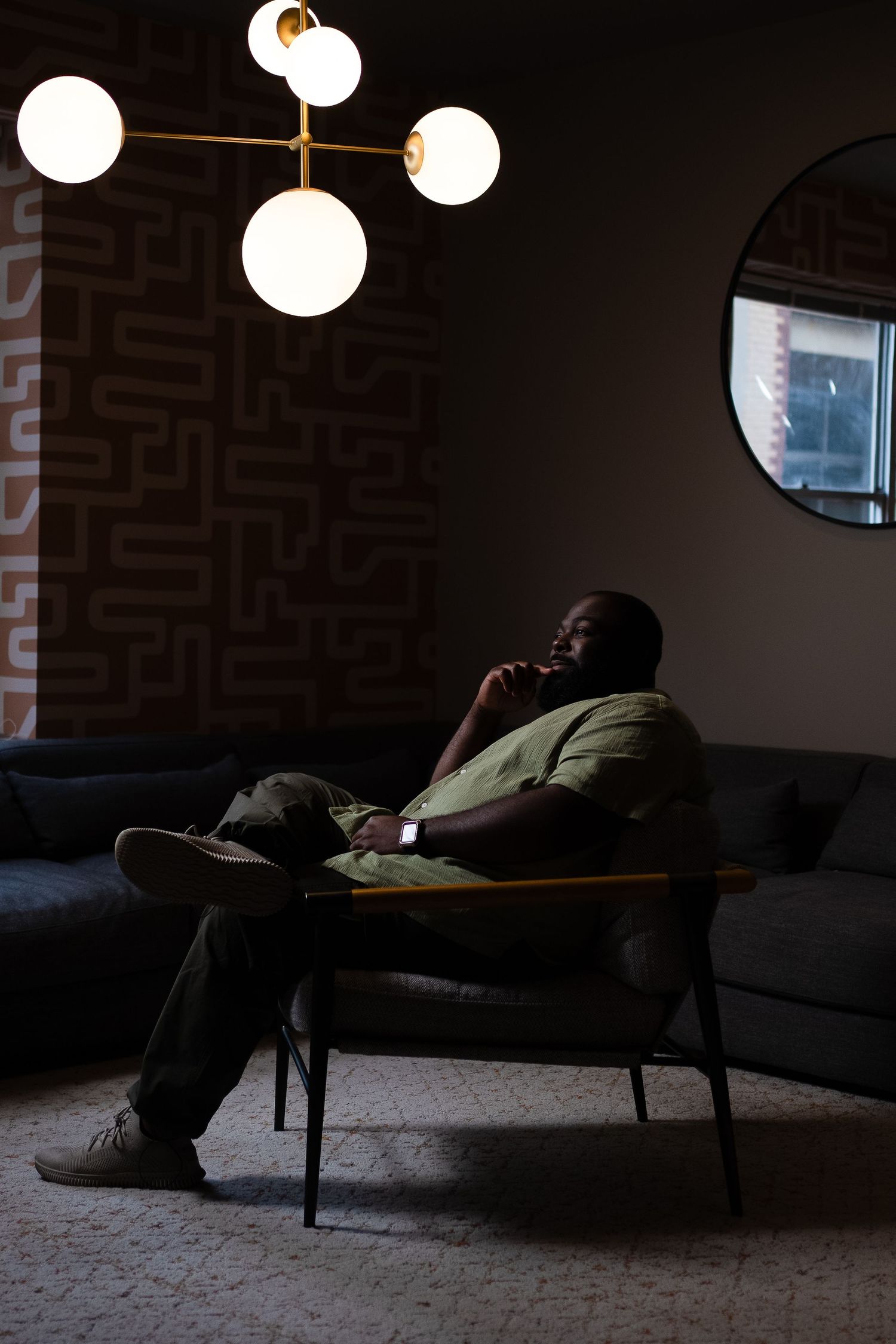 Dimly lit room with round pendant lights and person resting on dark couch.