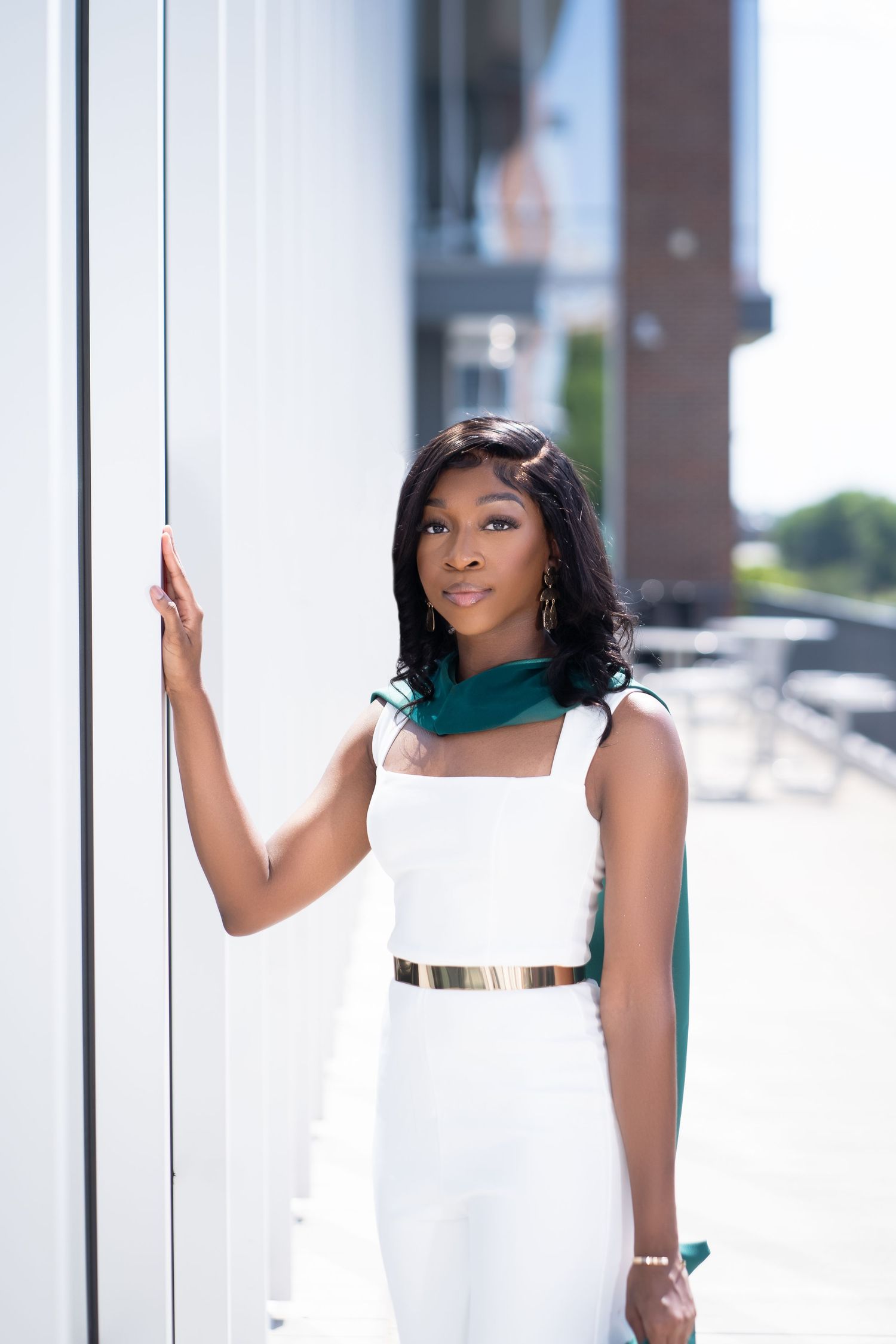 Fashion portraits in white dress against modern architectural background.