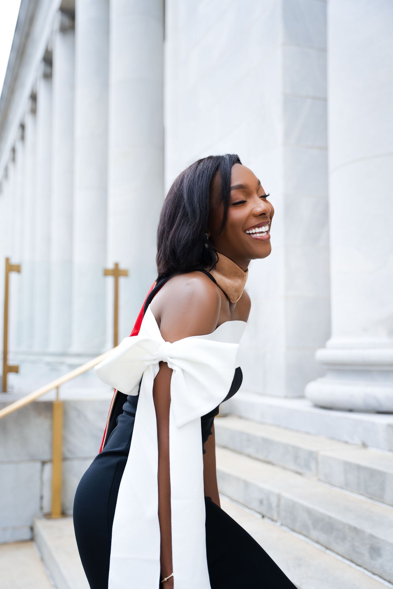 Elegant portrait with white bow detail dress against classical column architecture.