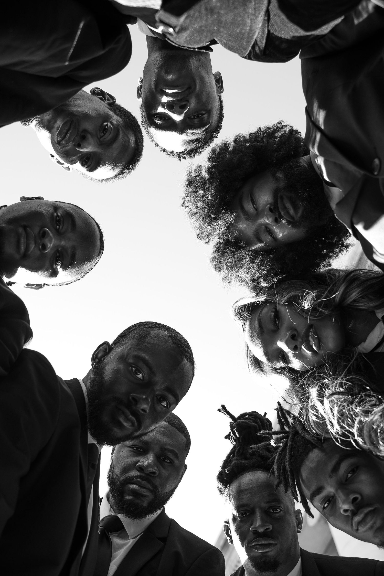 Group forms circle for creative overhead black and white portrait shot.