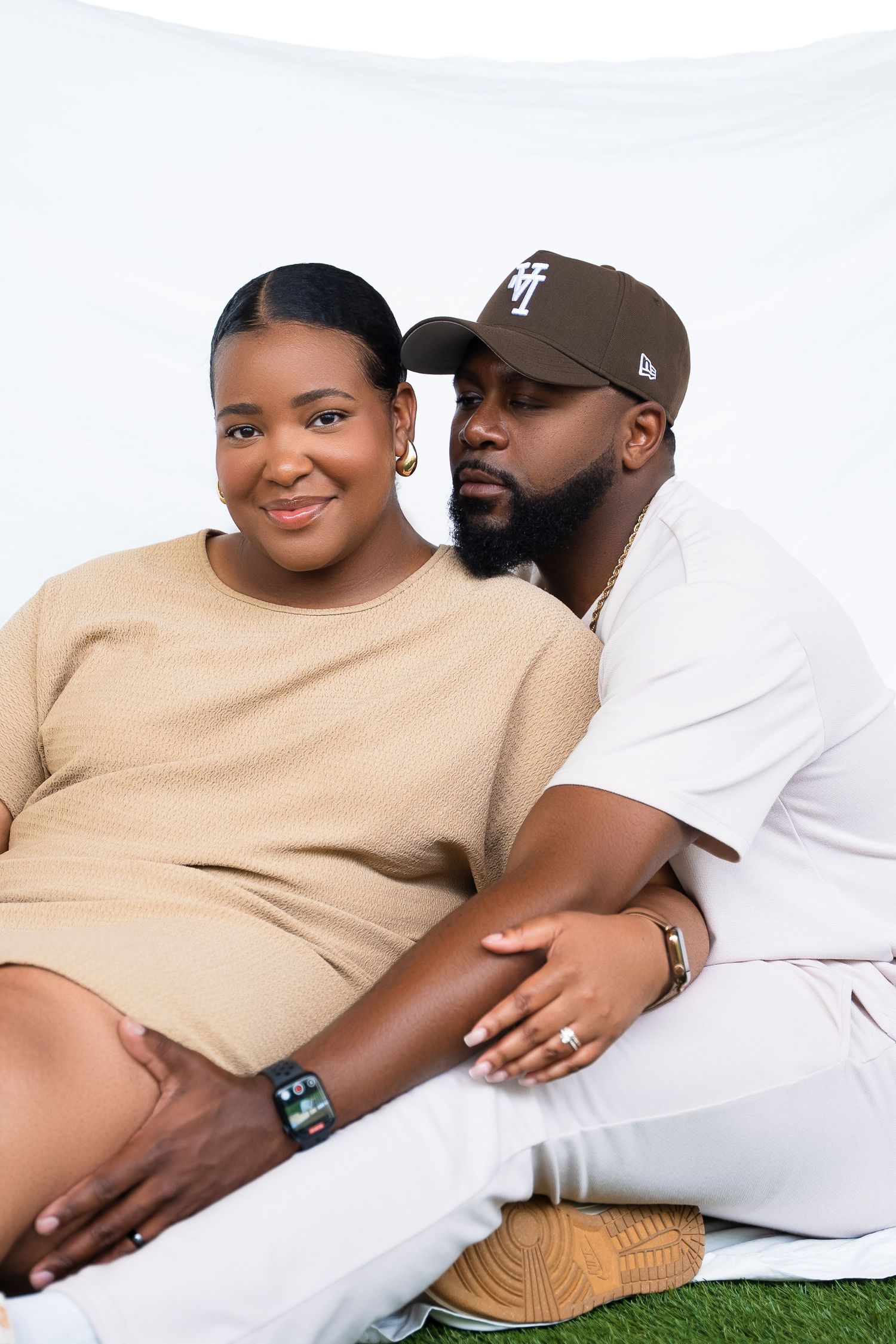 Couple in casual beige and white outfits poses intimately during outdoor photoshoot.