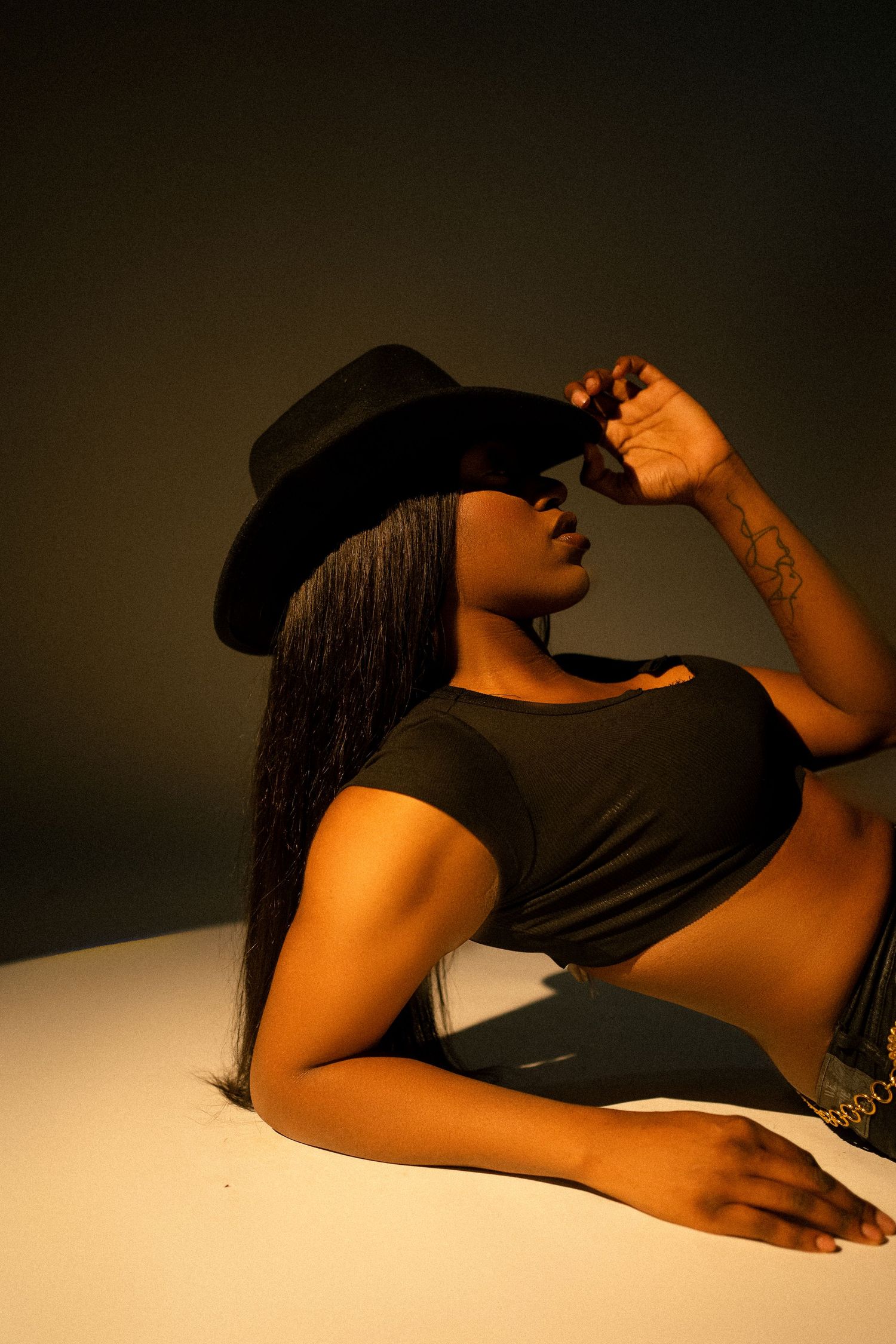 Artistic portrait in dramatic lighting with black hat and long straight hair.