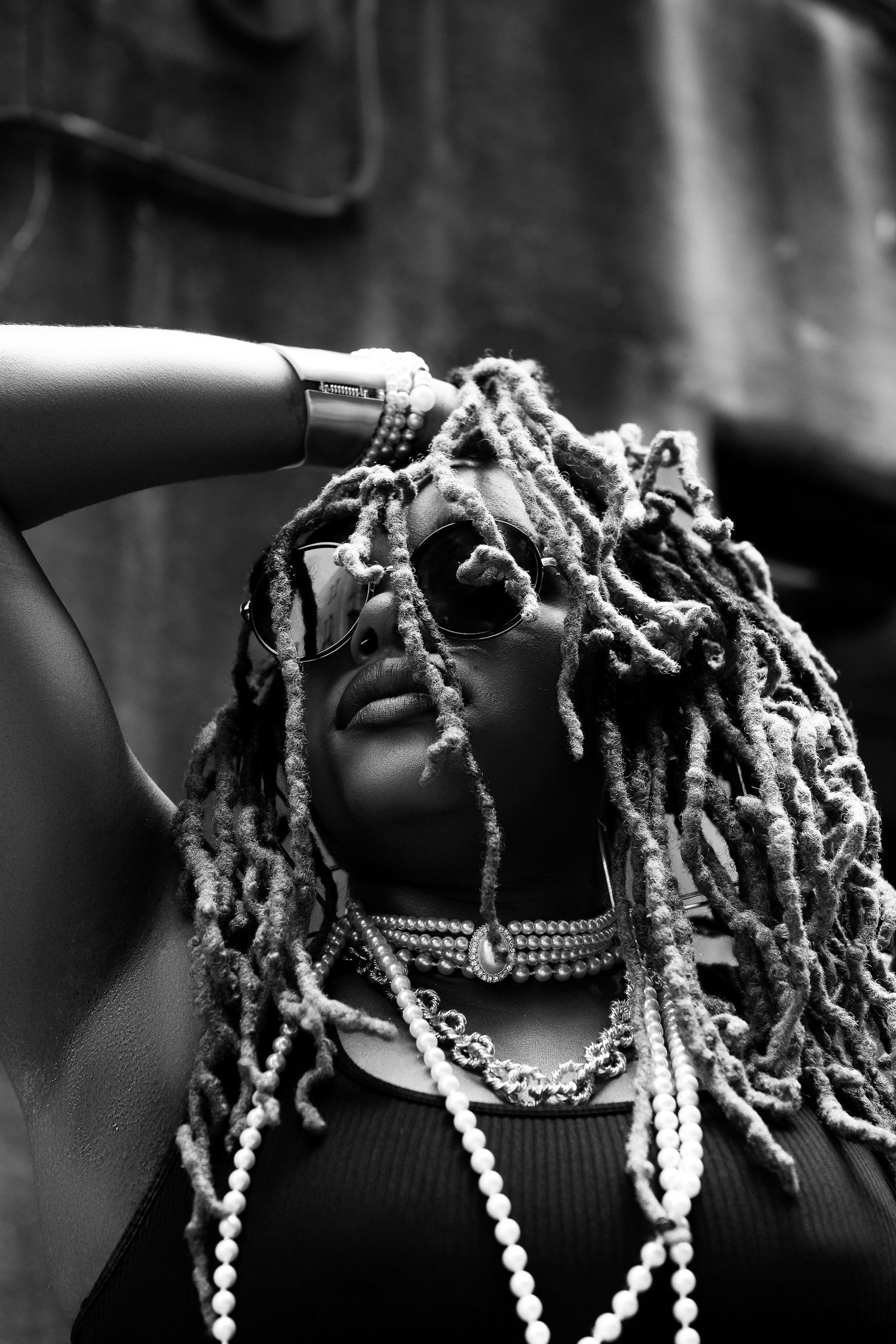 Dramatic black and white portrait showcasing textured hair and pearl necklaces.