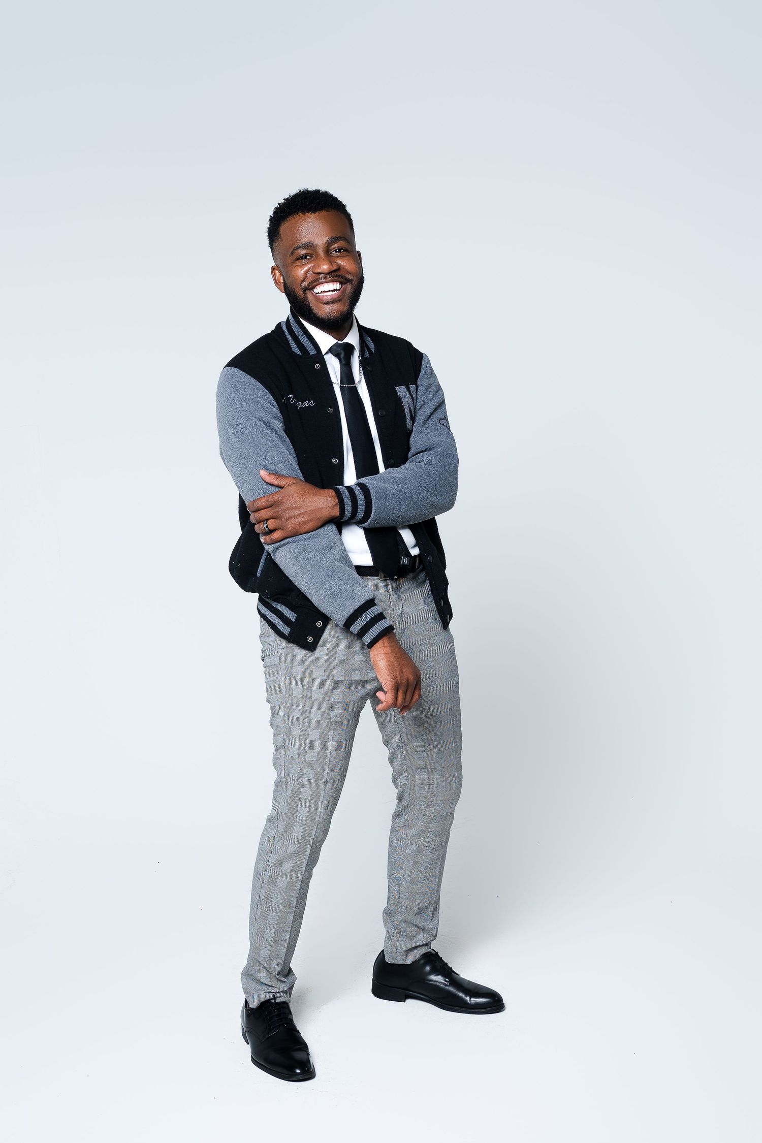 Person in black and gray varsity jacket and sweatpants poses against white background.