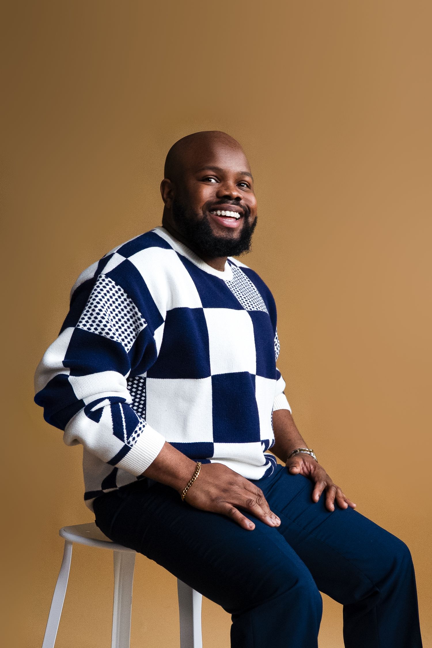 Stylish portrait against beige background wearing geometric patterned sweater.