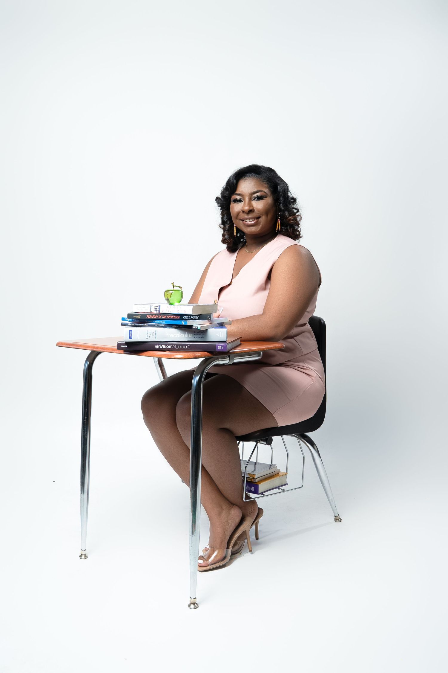 Professional seated at school desk with books and apple.