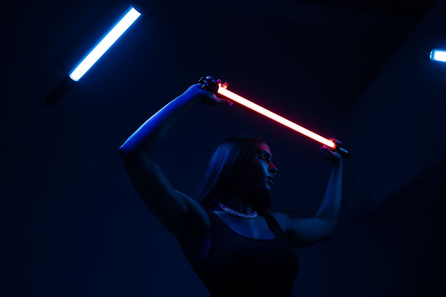 Silhouette holding glowing blue and red light sabers in dark setting.