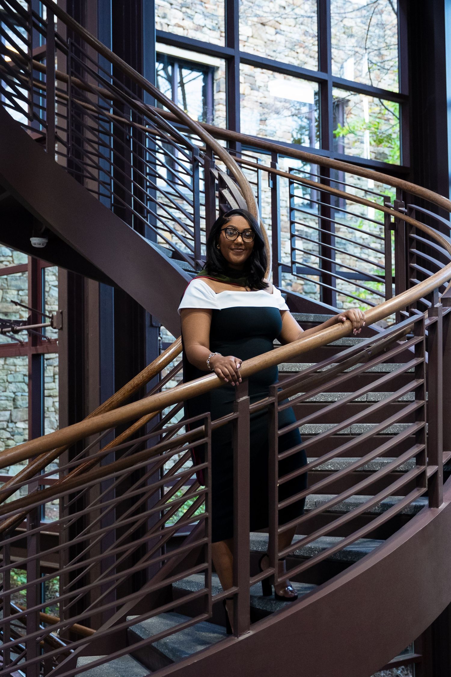 Elegant black and white dress captured on a modern spiral staircase with large windows.