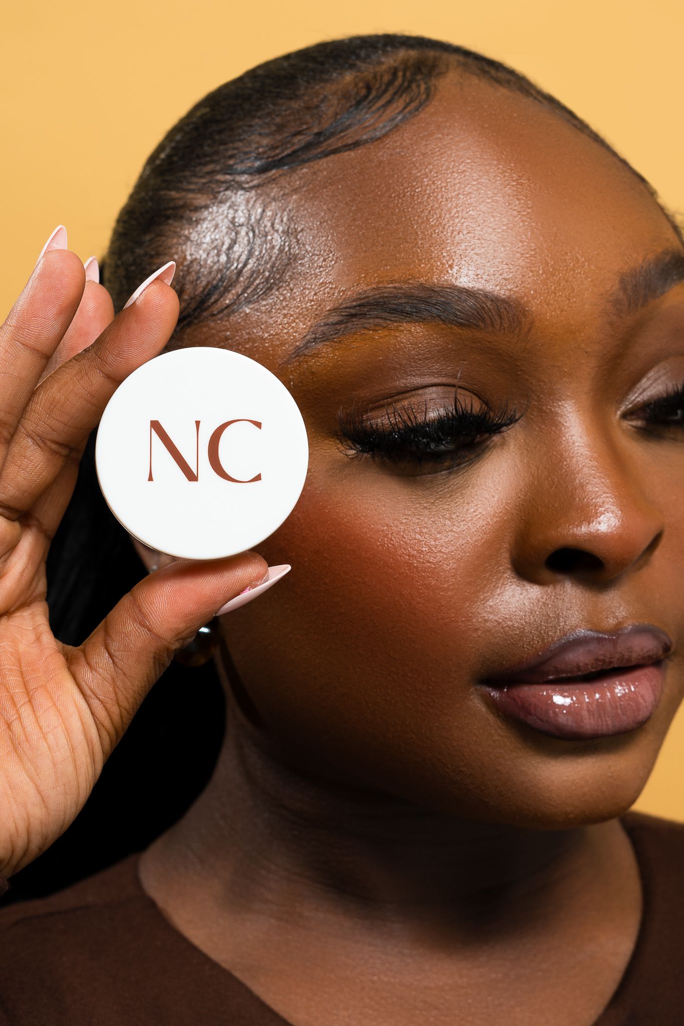 Beauty product shot featuring NC branded cosmetic container with elegant makeup styling.