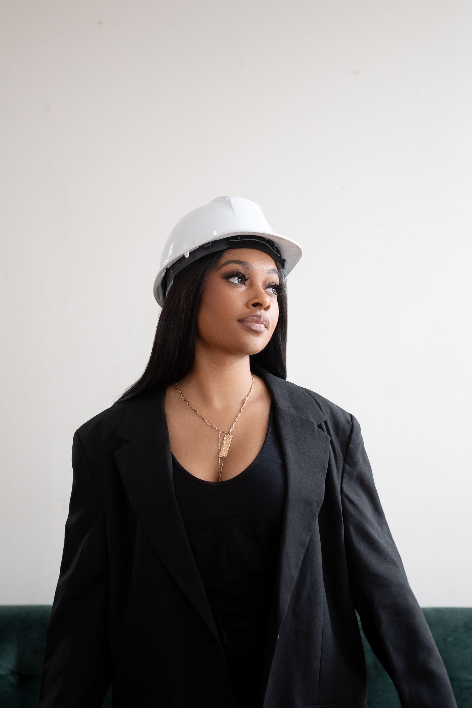 Professional wearing hard hat and blazer in modern industrial setting.