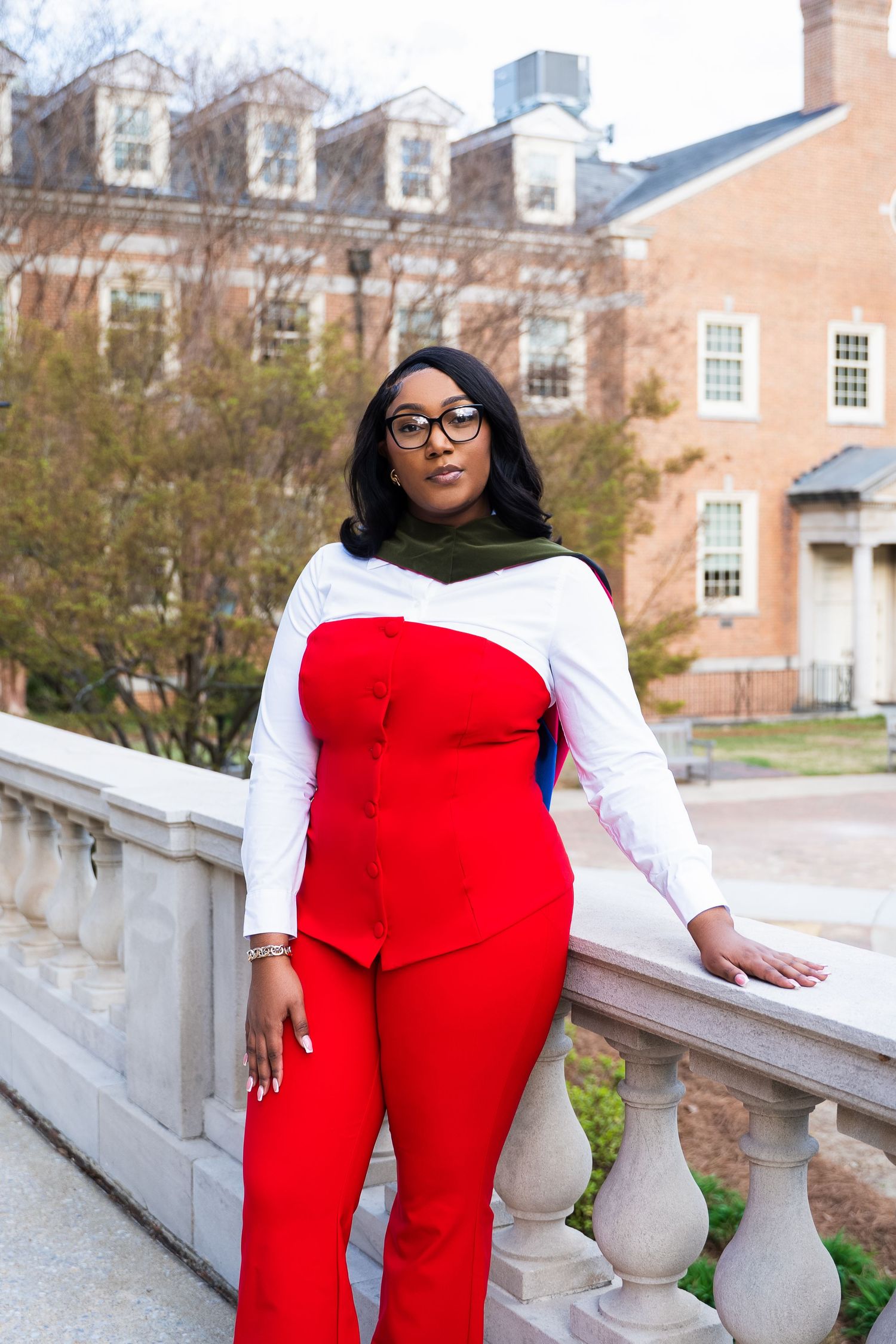 Professional photo of a stylish red and white jumpsuit outfit against a brick building with classic architecture.