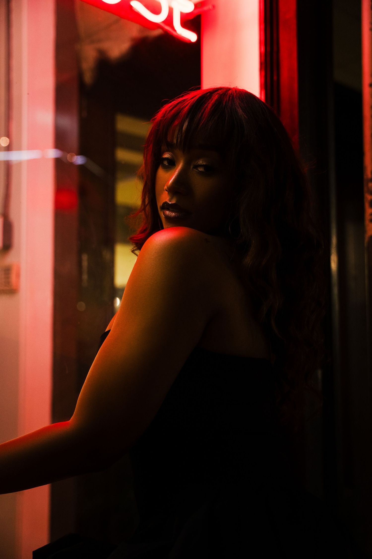 Person in silhouette against red neon lights in a dark urban nightlife setting.