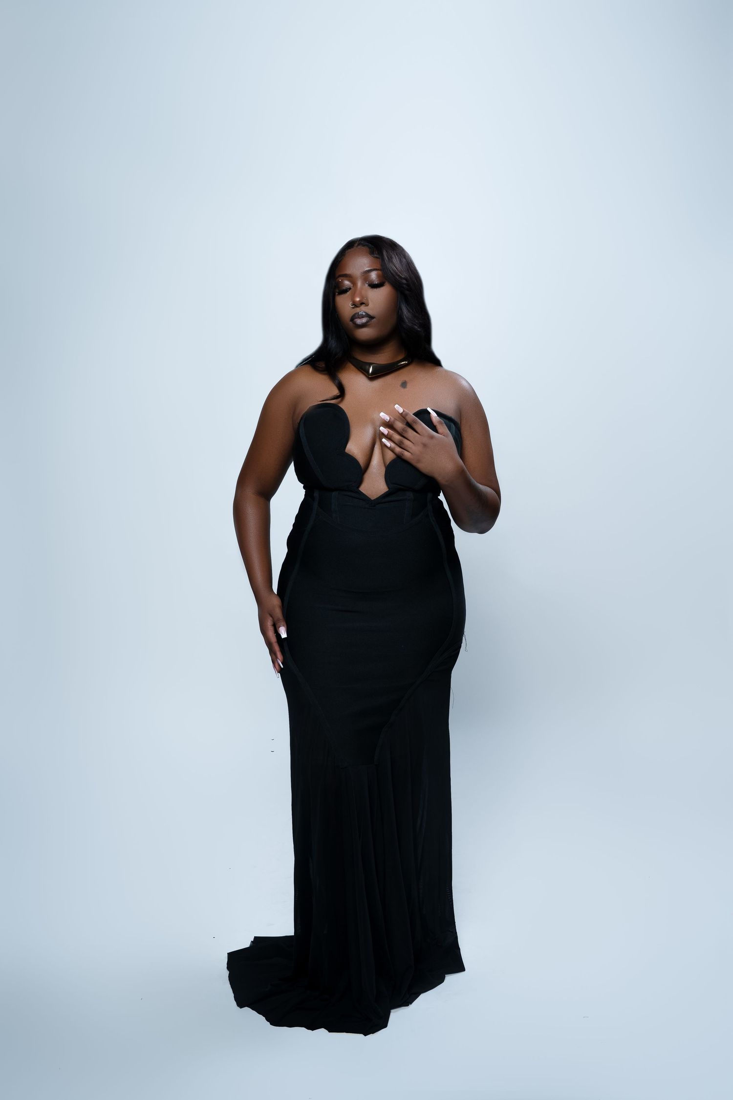 A fashion photoshoot featuring a black dress against a white backdrop.