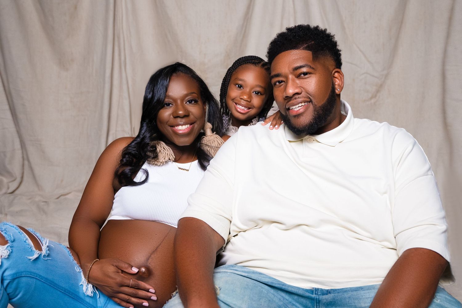 Heartwarming family portrait with parents and child against neutral background.