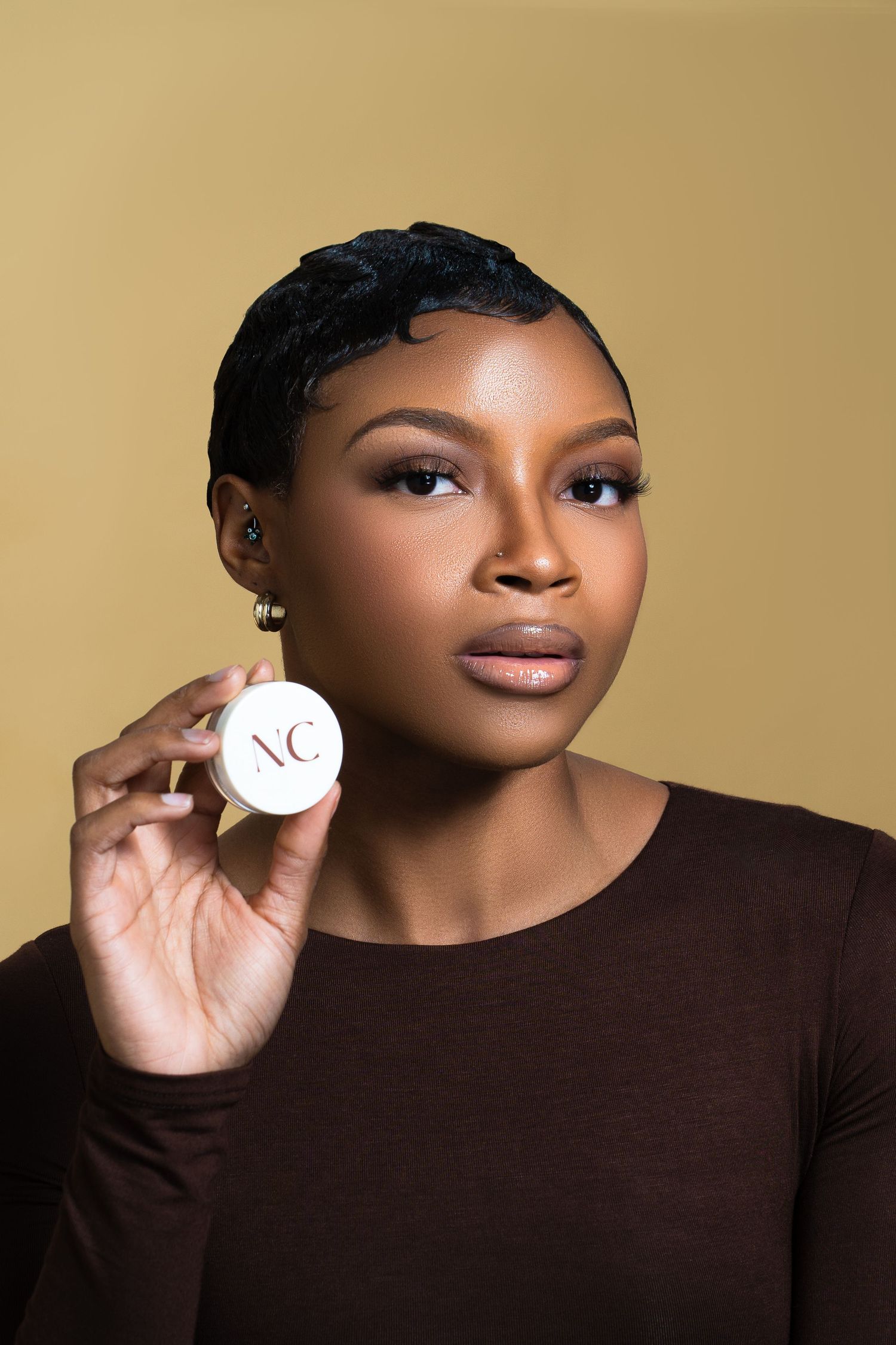 Beauty product photography featuring NC branded cosmetic container against brown background.