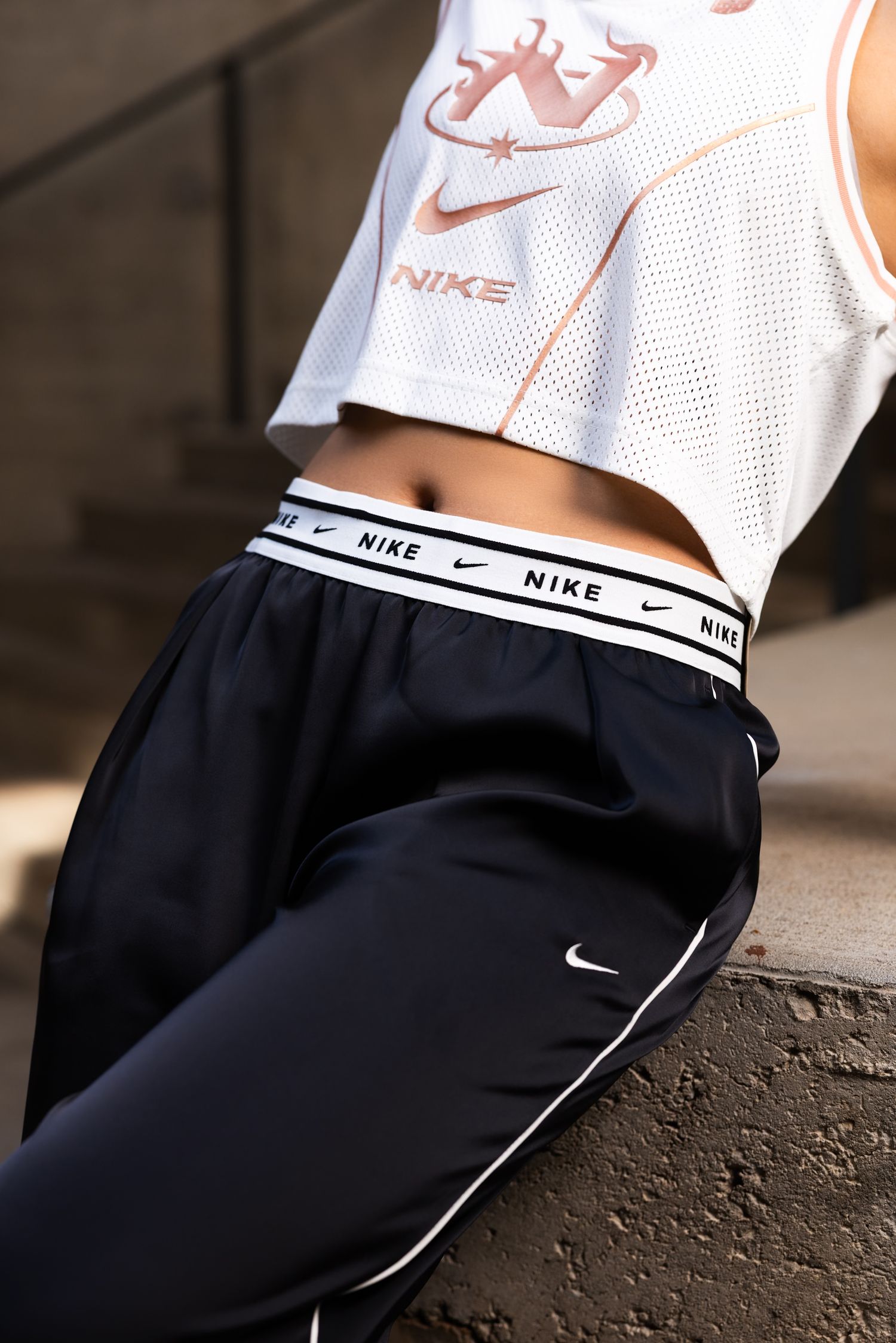 Nike sportswear close-up showing white mesh top and black shorts with branded waistband detail.