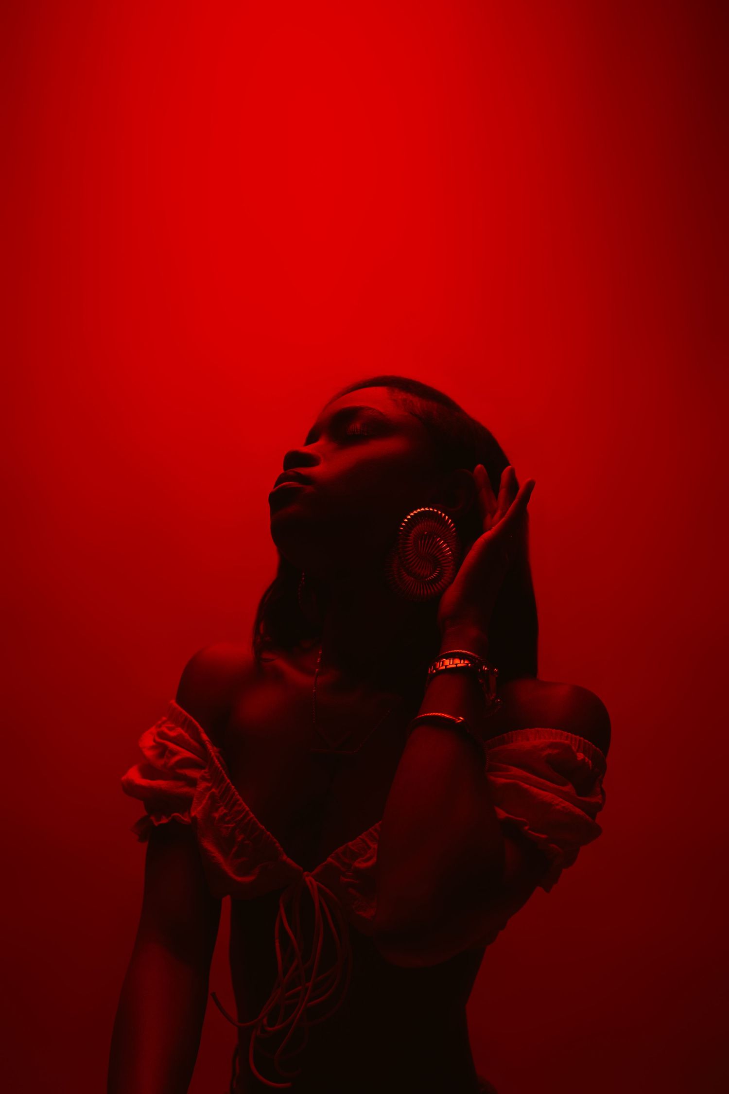 Silhouetted figures cast in dramatic red lighting create a moody artistic composition against a dark background.