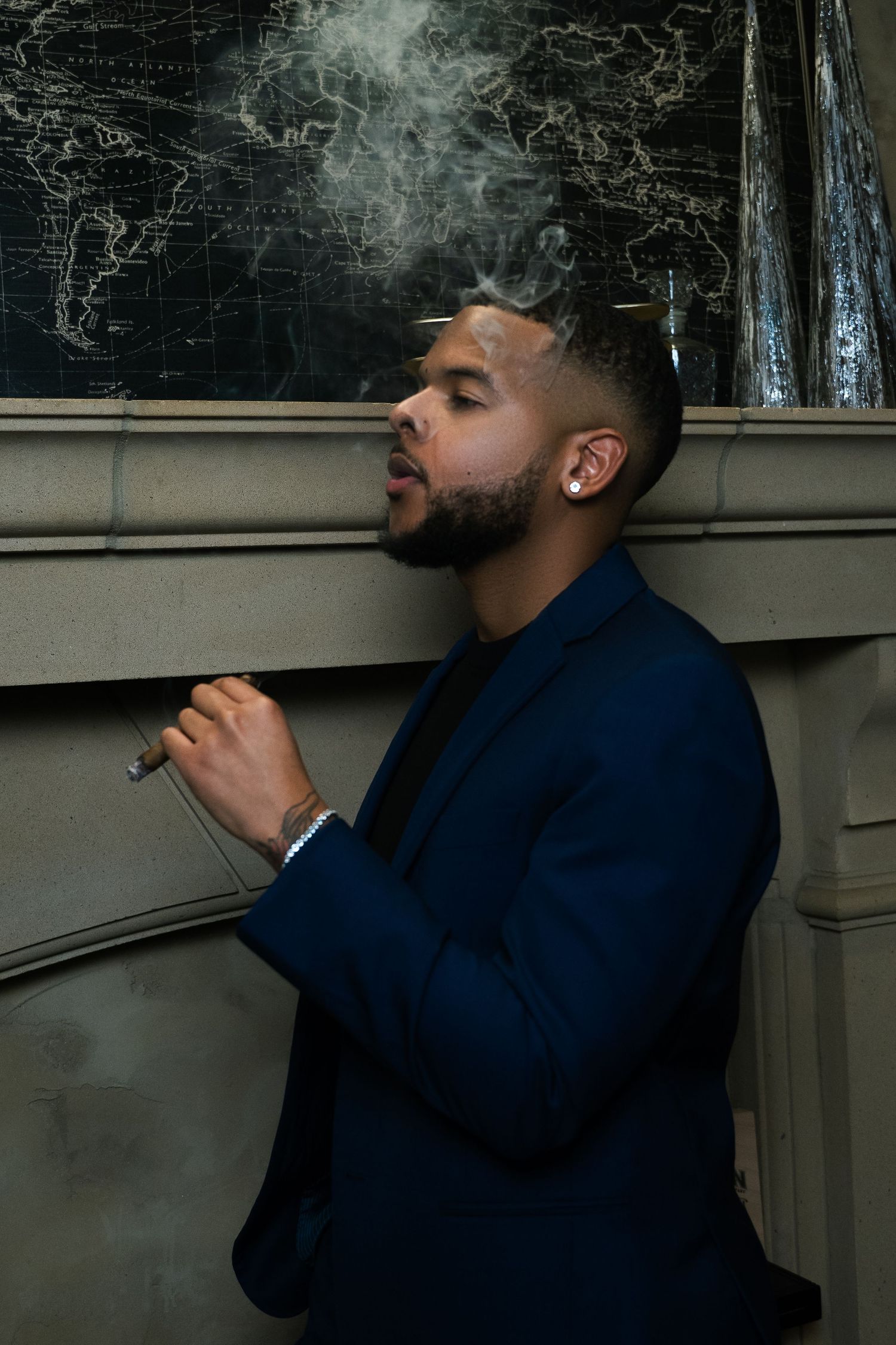 Stylish portrait in blue suit with smoke effect against dark wall.