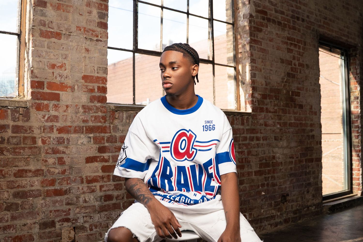 Vintage-style Atlanta Braves baseball jersey in white with blue lettering in industrial setting.