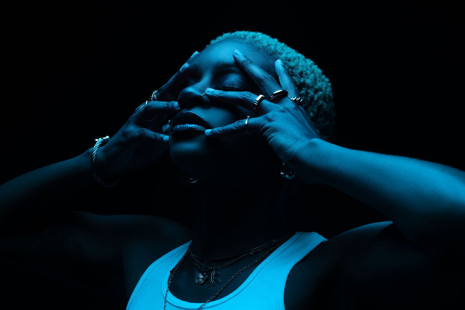 Figure in athletic wear illuminated by blue light against dark background.