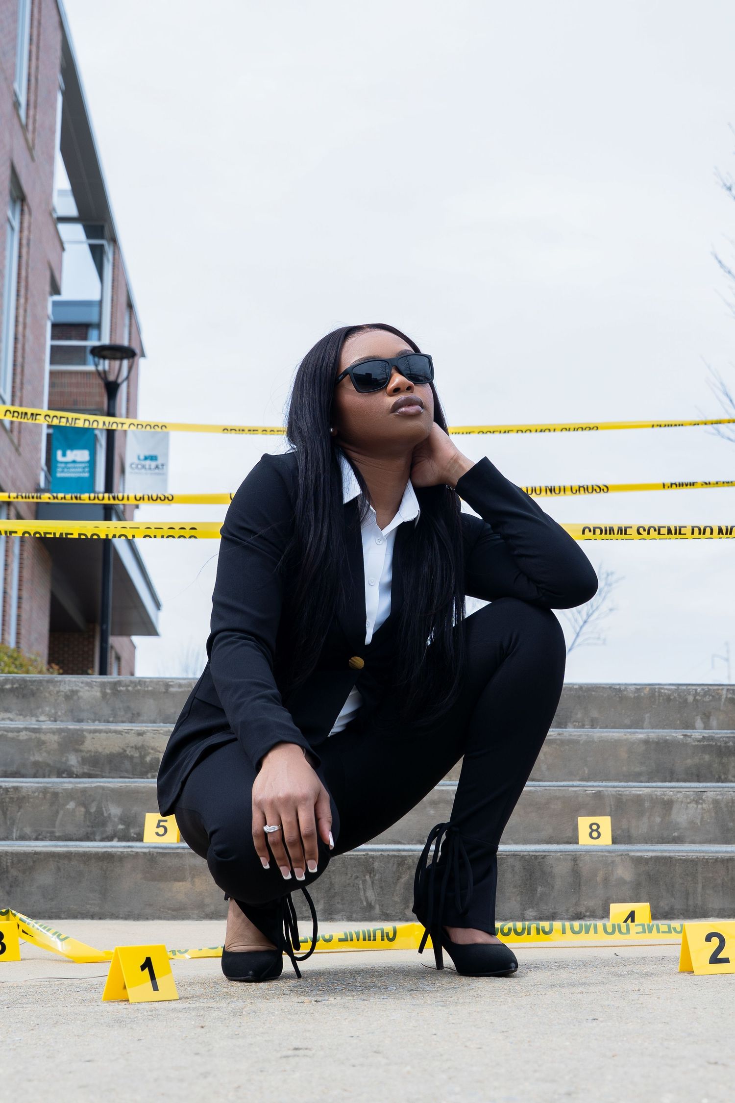 Professional in suit poses on steps with crime scene tape.