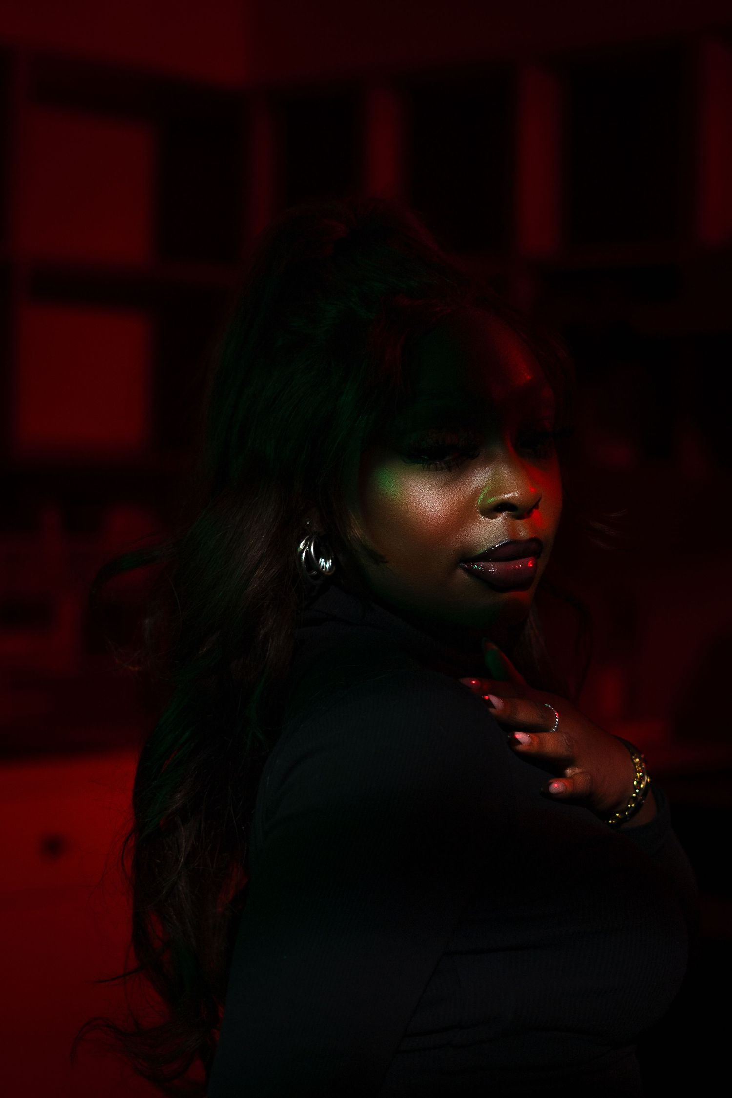 Stylish portrait with red and green lighting effects creating mysterious ambiance.