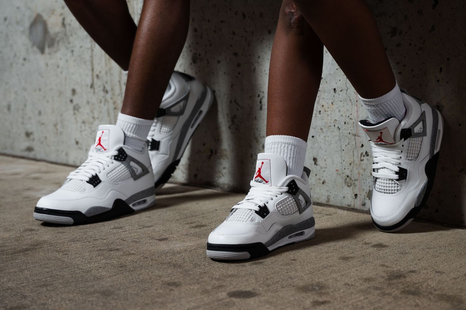 Close-up view of white Air Jordan sneakers against concrete wall.