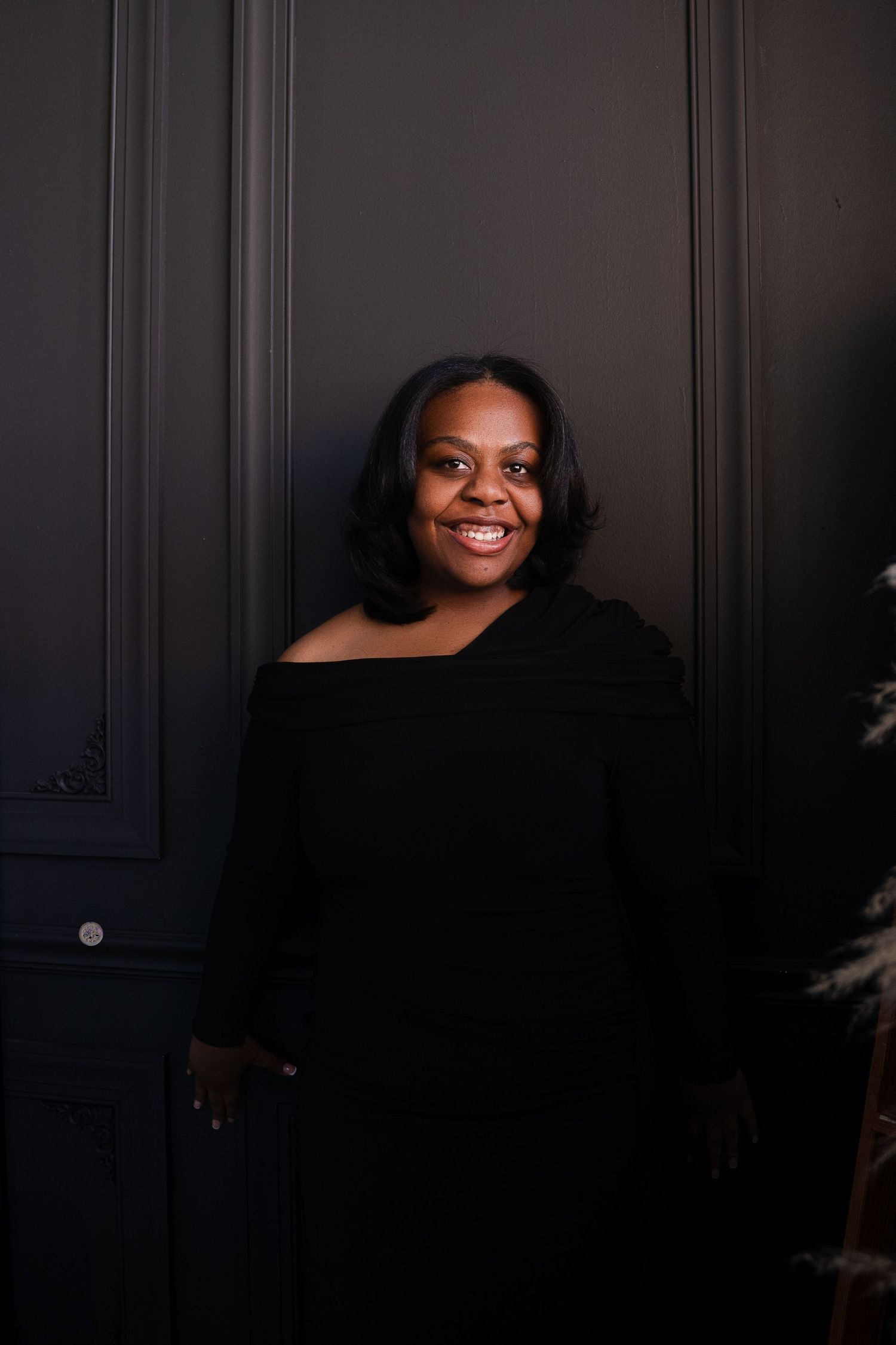 Moody portrait series in black attire against dark paneled backdrop.