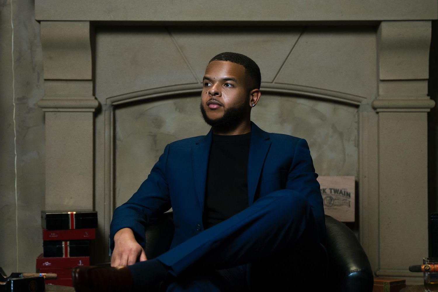 Elegant portrait session in fitted blue suit against dark background.