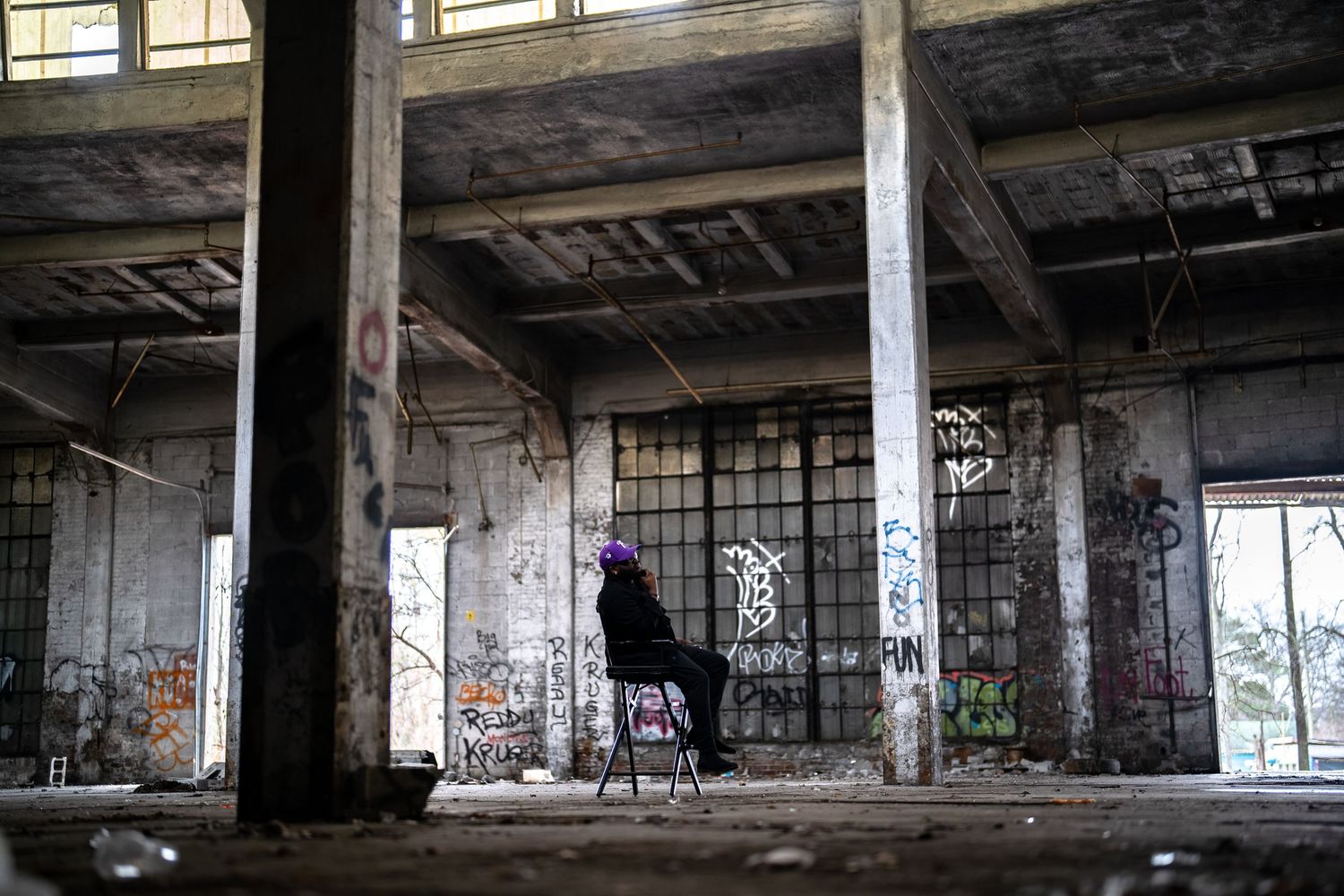 Empty industrial warehouse space showing concrete pillars and graffiti covered walls.