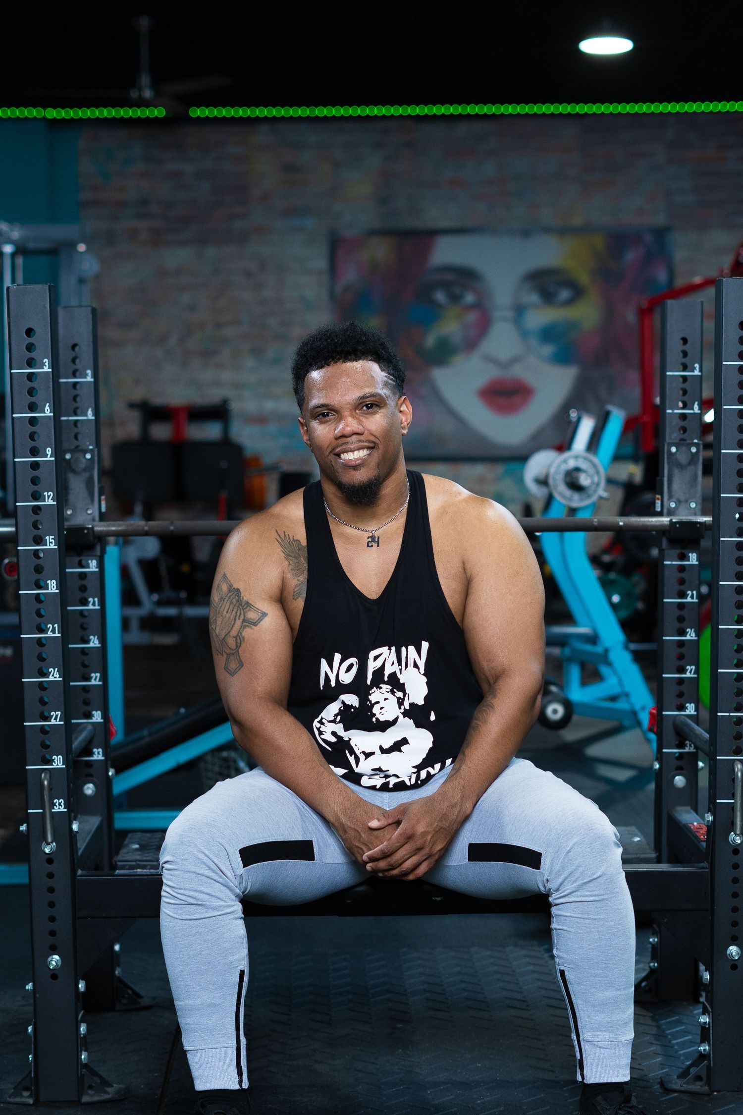 Fitness portrait in black tank top at gym with weight equipment.