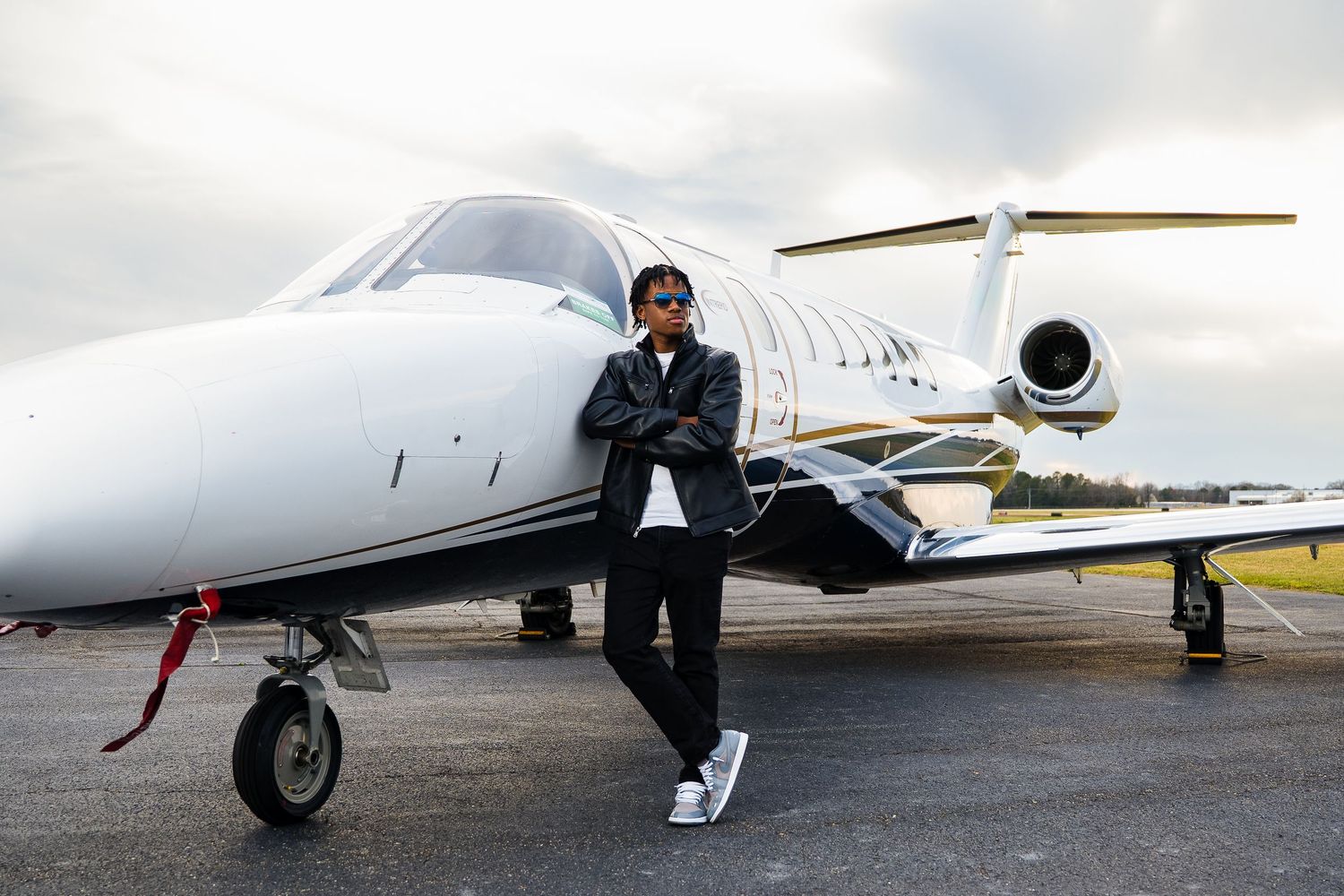 Stylish traveler posed in front of a private jet on an overcast day.