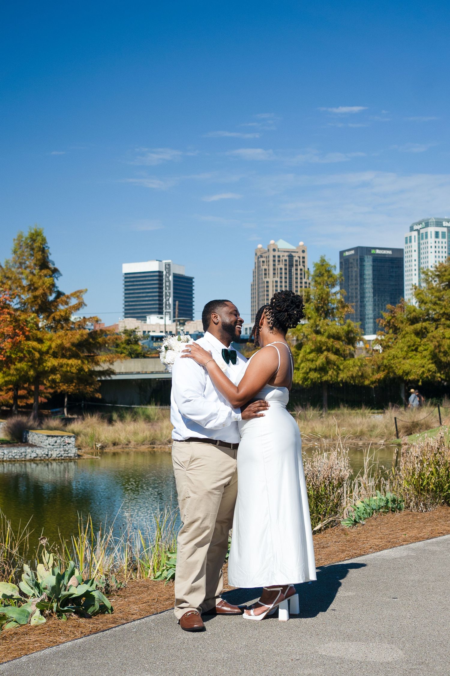 A romantic moment shared between a couple along an urban waterfront path on a sunny day.